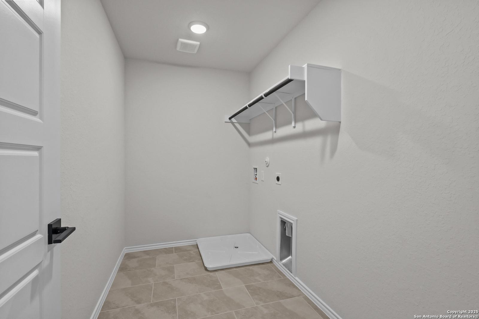 Bright laundry room with white built-in shelves, washer-dryer hookups, and pet door in Davidson Homes The Florence C, San Antonio