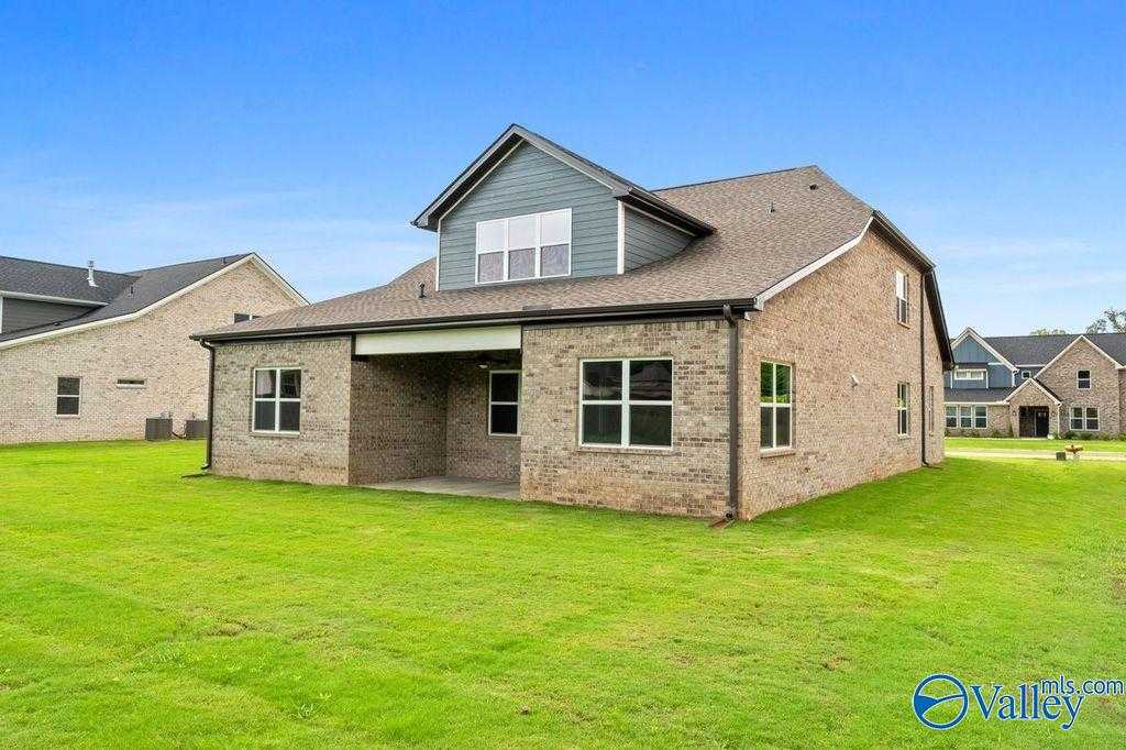 Side view of modern brick Oxford home with covered patio, large windows, and lush green yard in The Meadows at Hampton Cove, Owens Cross Roads, Alabama