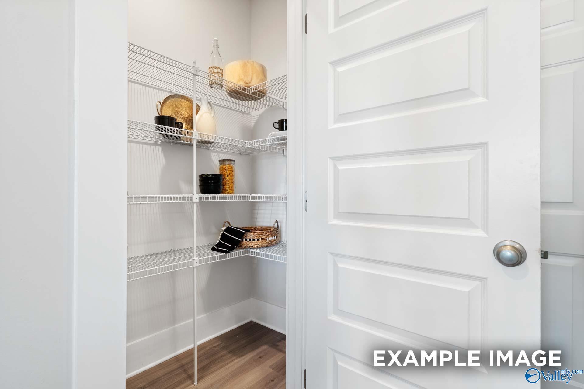 Spacious walk-in pantry with white wire shelving and wood-look flooring in Davidson Homes Chelsea A plan, Ivy Hills, Toney, Alabama