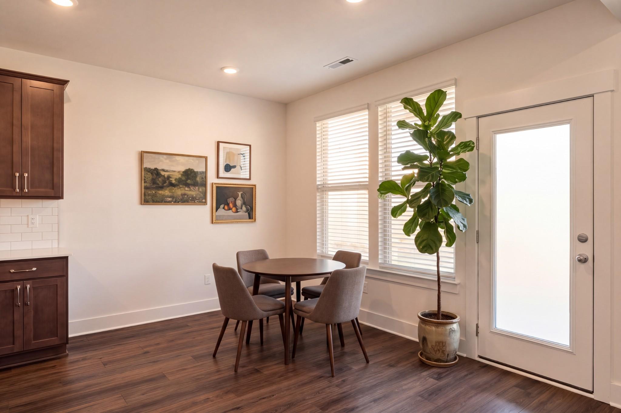Bright breakfast nook with hardwood floors, round dining table, and fiddle leaf fig in Davidson Homes Willow C, Gallatin TN
