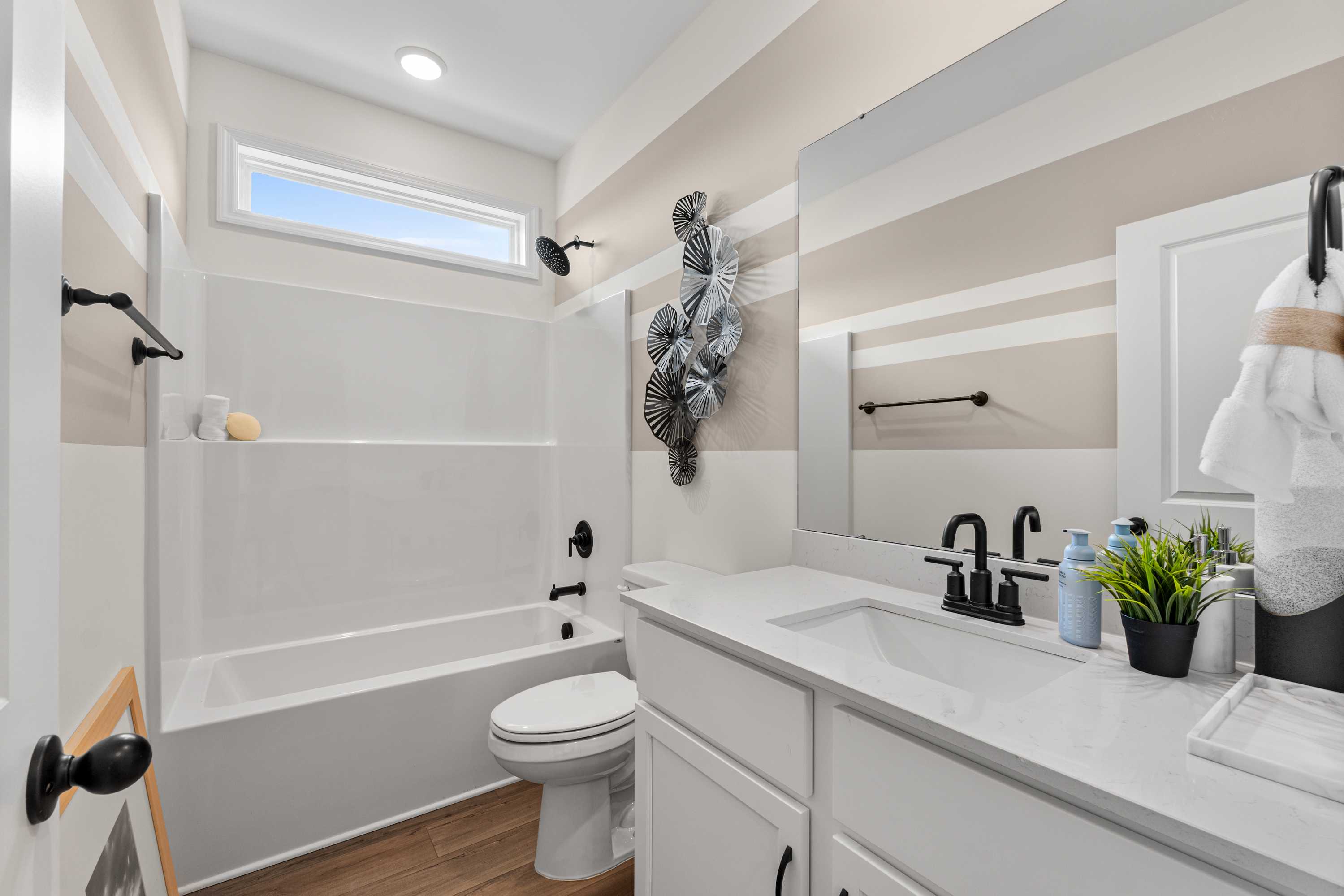 Bright bathroom in Lynn Meadows Meridianville Alabama with white subway tile tub-shower, quartz vanity, and seashell wall decor