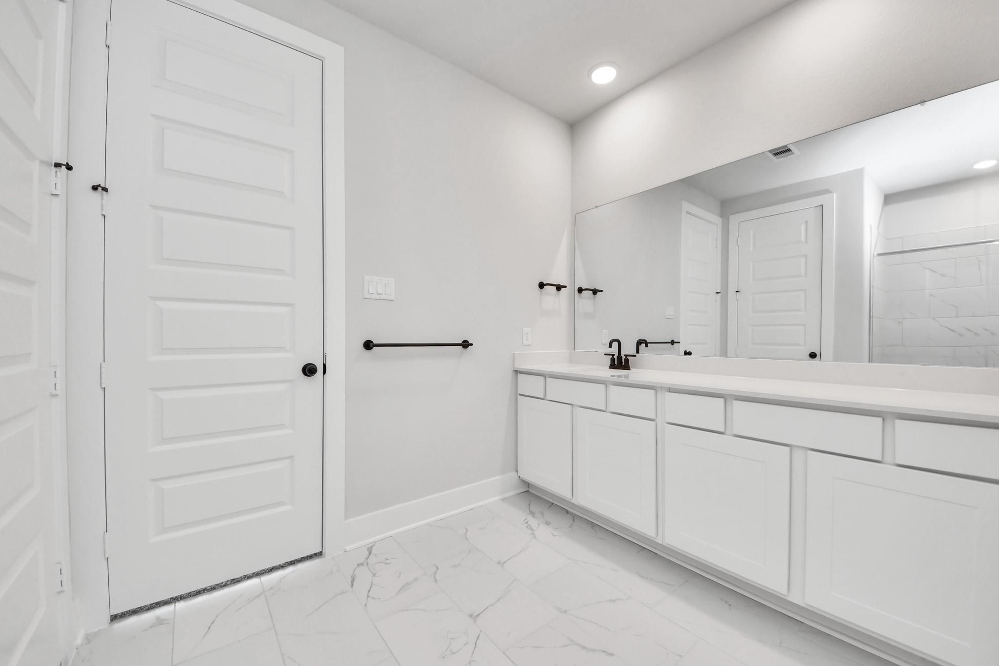 Modern bathroom with white vanity and marble-style flooring in The Laguna C floor plan by Davidson Homes in Katy, Texas.
