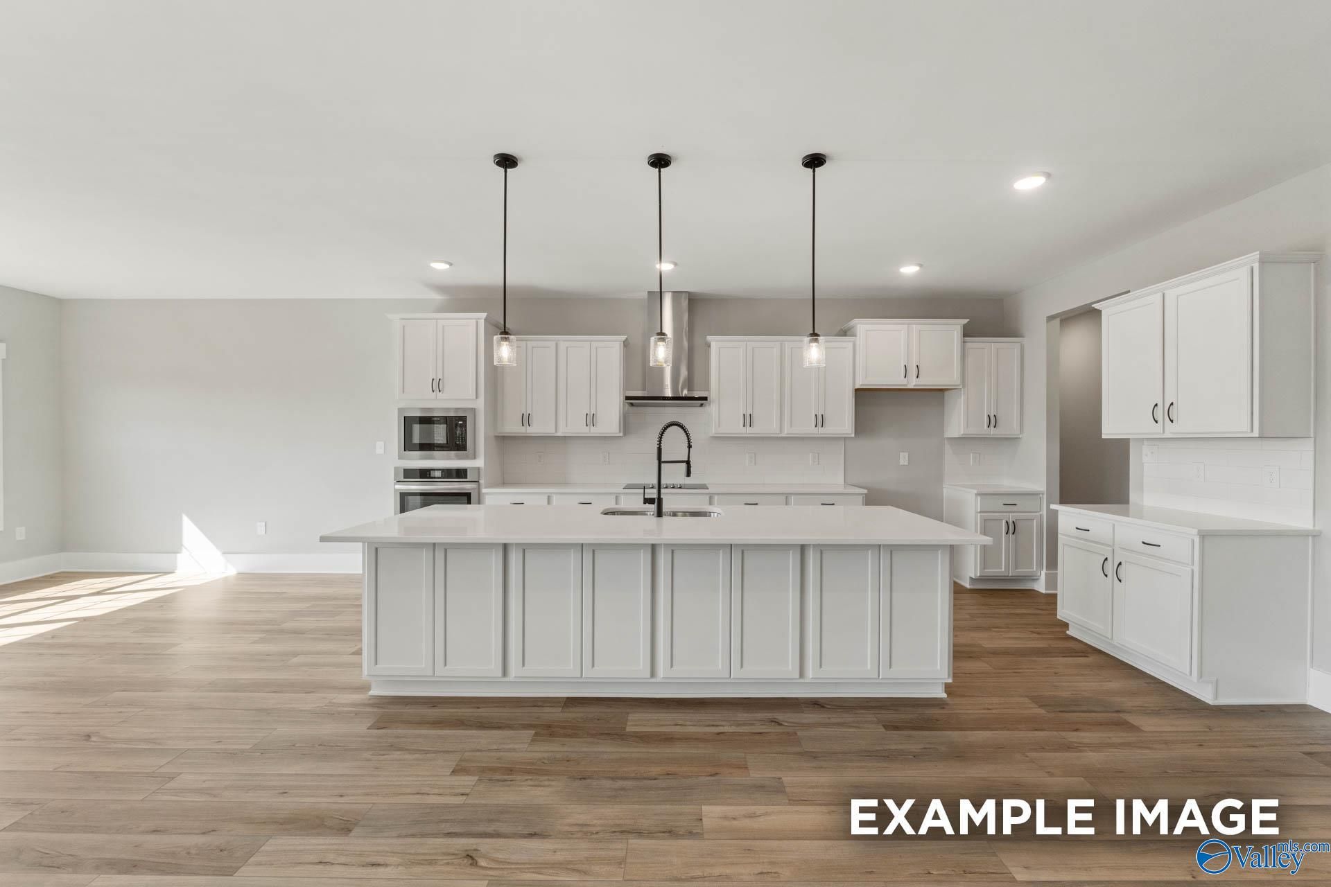 Modern white kitchen with large island and pendant lighting in The Finleigh floor plan, Briercreek, Meridianville, AL.