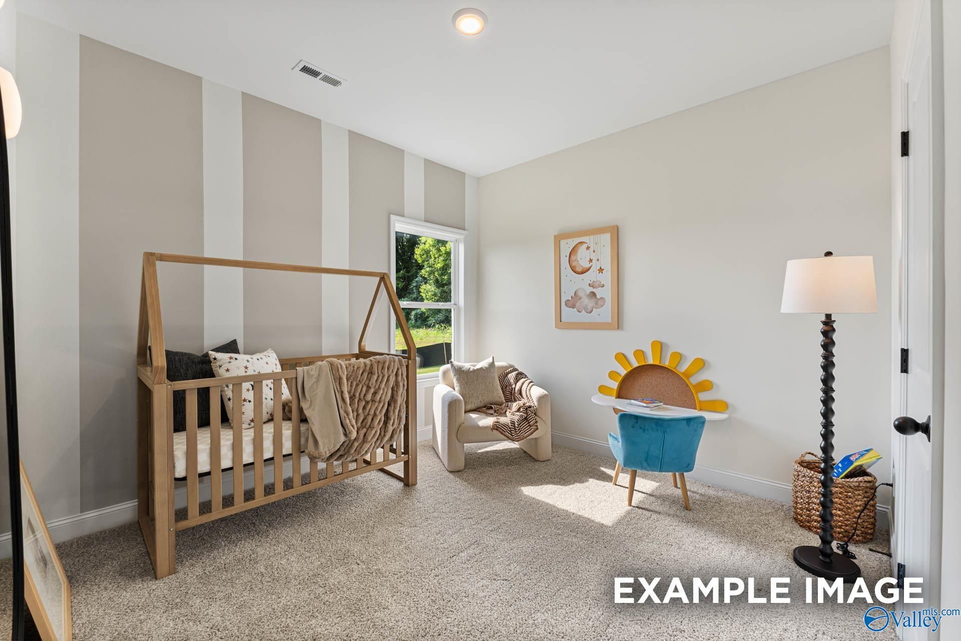 Cozy nursery featuring wooden crib, plush armchair, and whimsical sun decor in The Franklin 3-bedroom home, Huntsville, Alabama