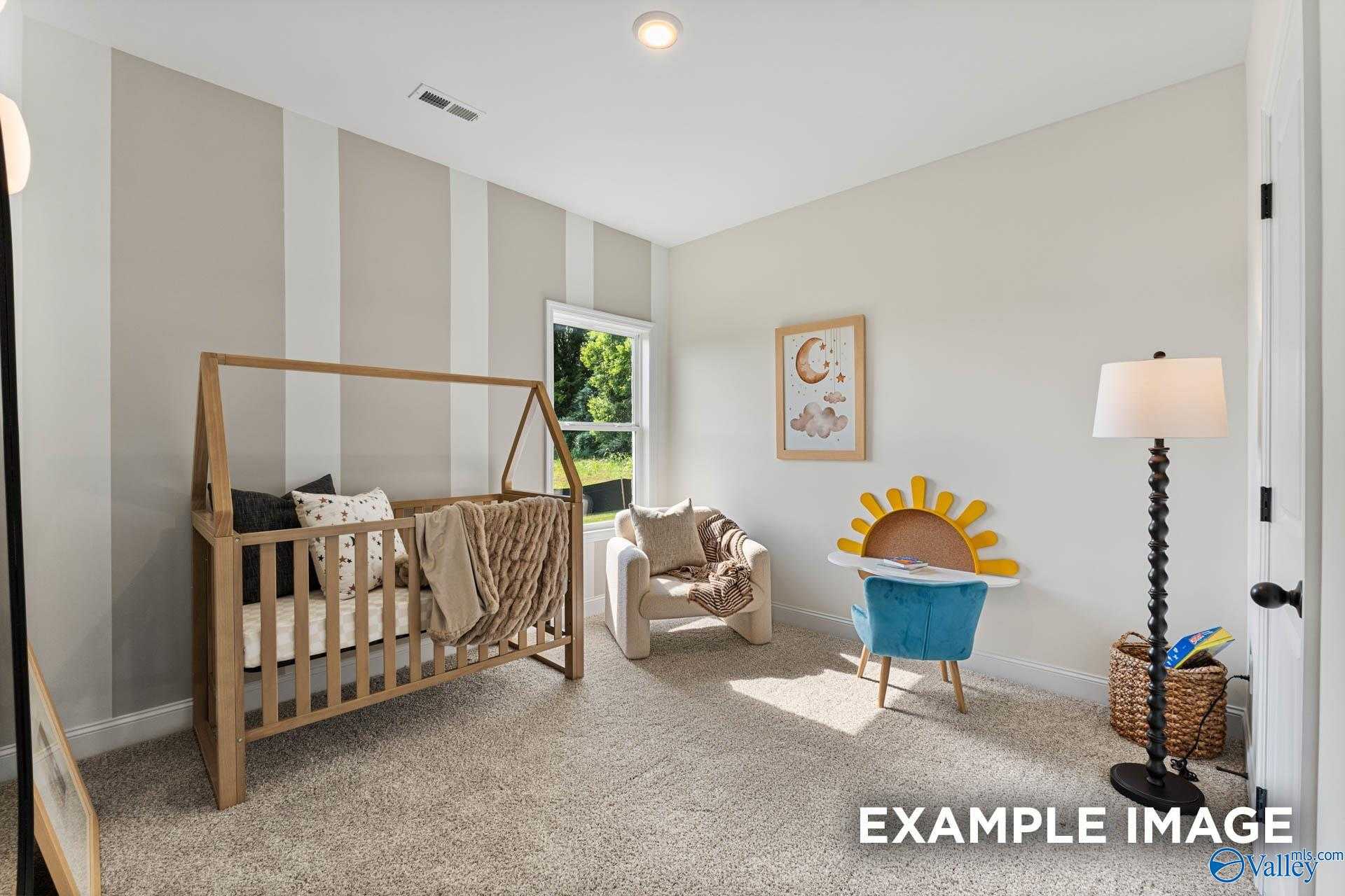 Cozy nursery with A-frame wooden crib, beige armchair, striped walls, and moon decor in The Franklin 3-bedroom home, Huntsville
