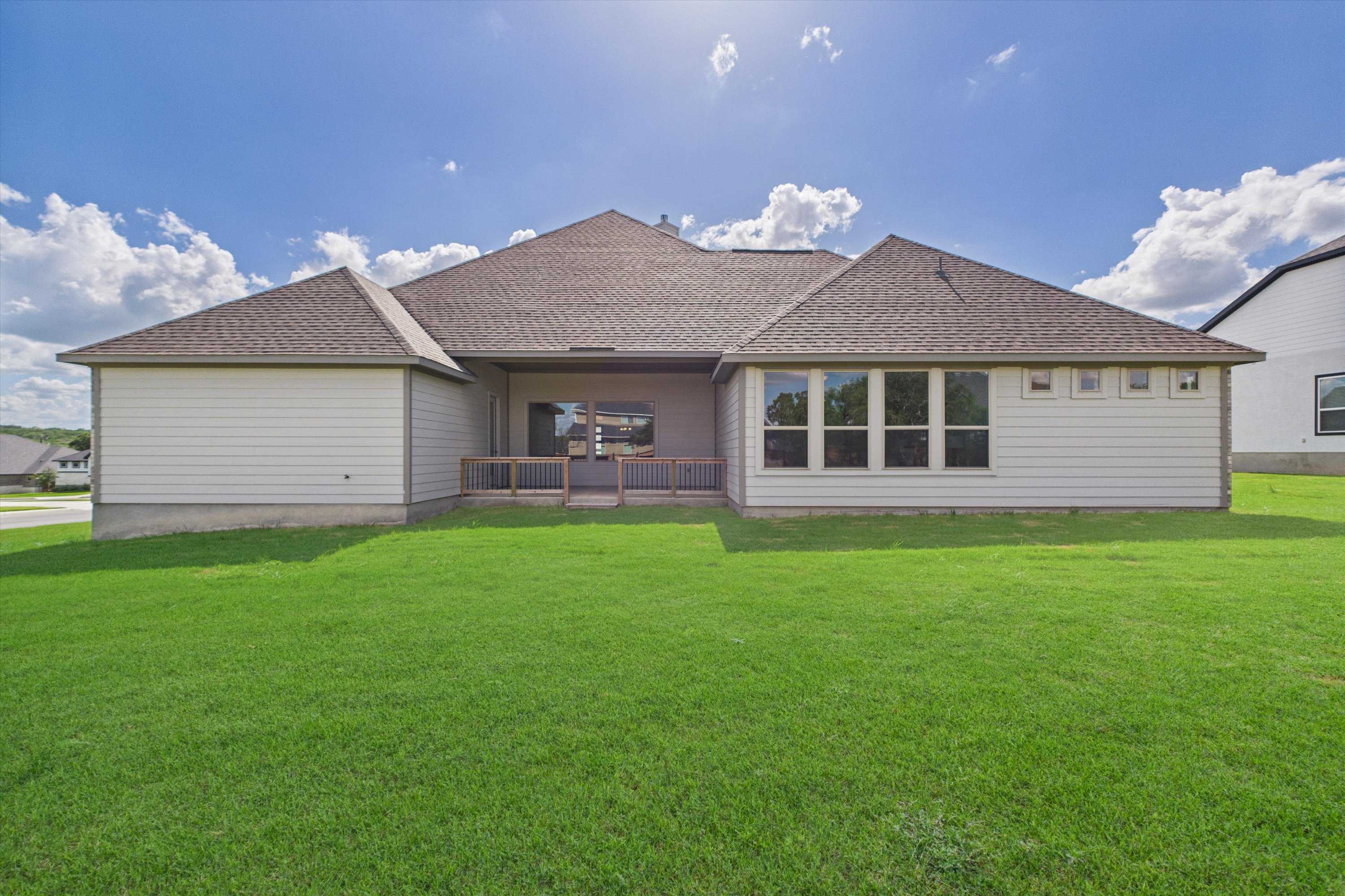 Rear view of Davidson Homes The Summerlin C with covered patio, large windows, and lush green backyard in Potranco Oaks, Castroville, Texas