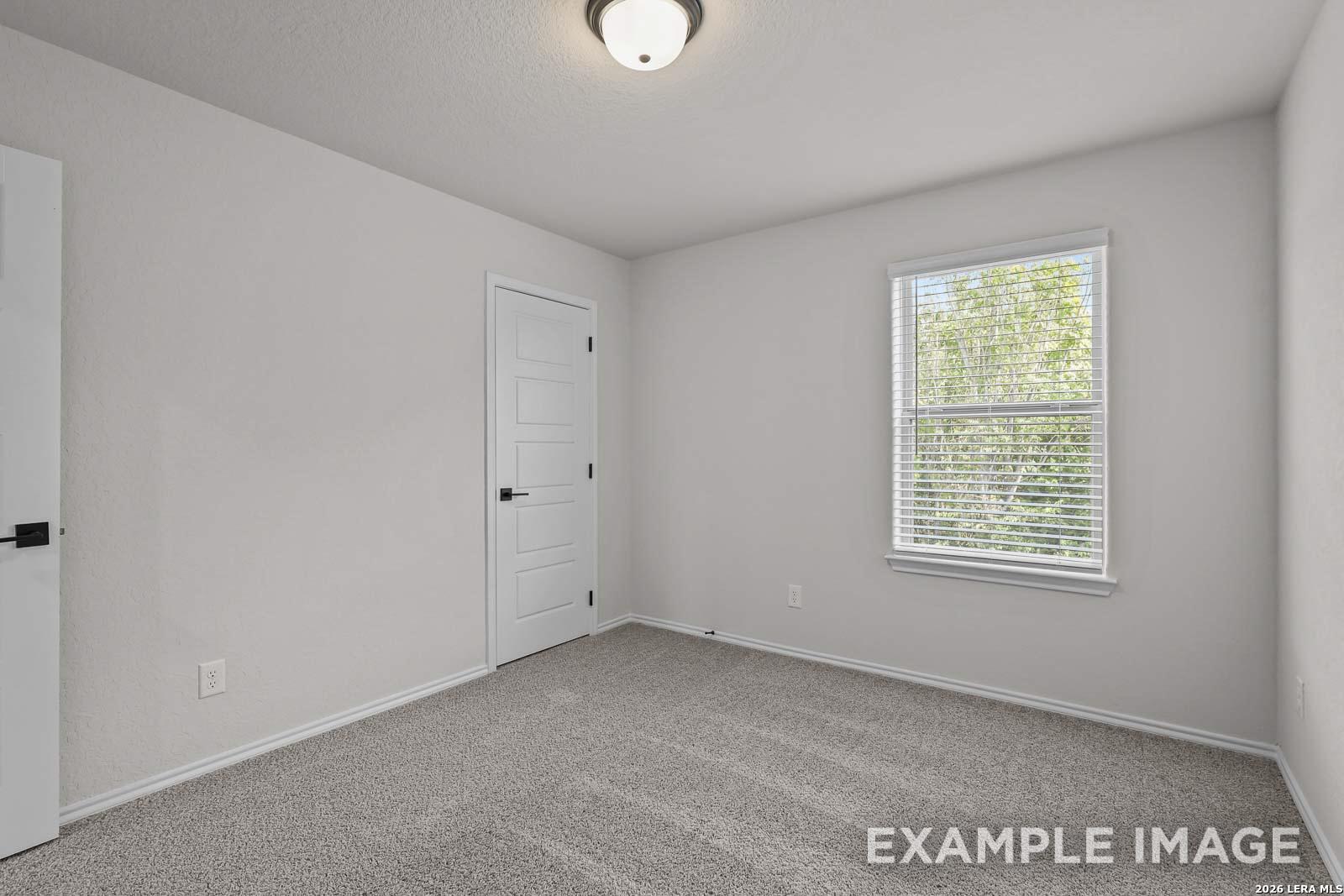 Bright secondary bedroom with neutral carpet and window in The Florence D floor plan by Davidson Homes, San Antonio, TX.