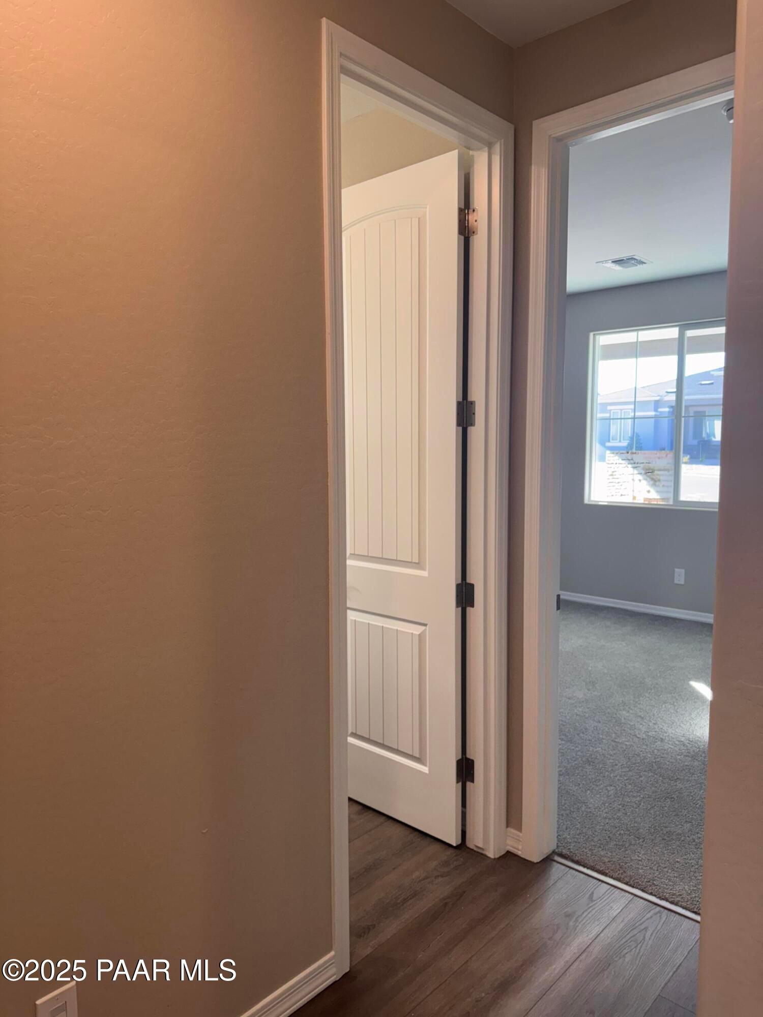 Beige hallway with open white paneled doors to carpeted bedroom and window view in 3-bedroom Davidson Homes Sunrise II A, Prescott AZ