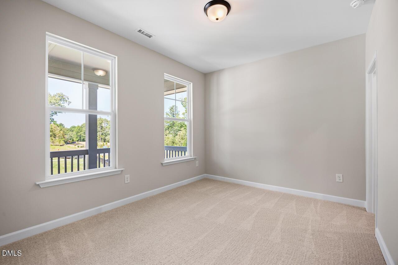 Bright, carpeted bedroom with large windows in The Chestnut floor plan by Davidson Homes in Montrose, Aberdeen, NC.