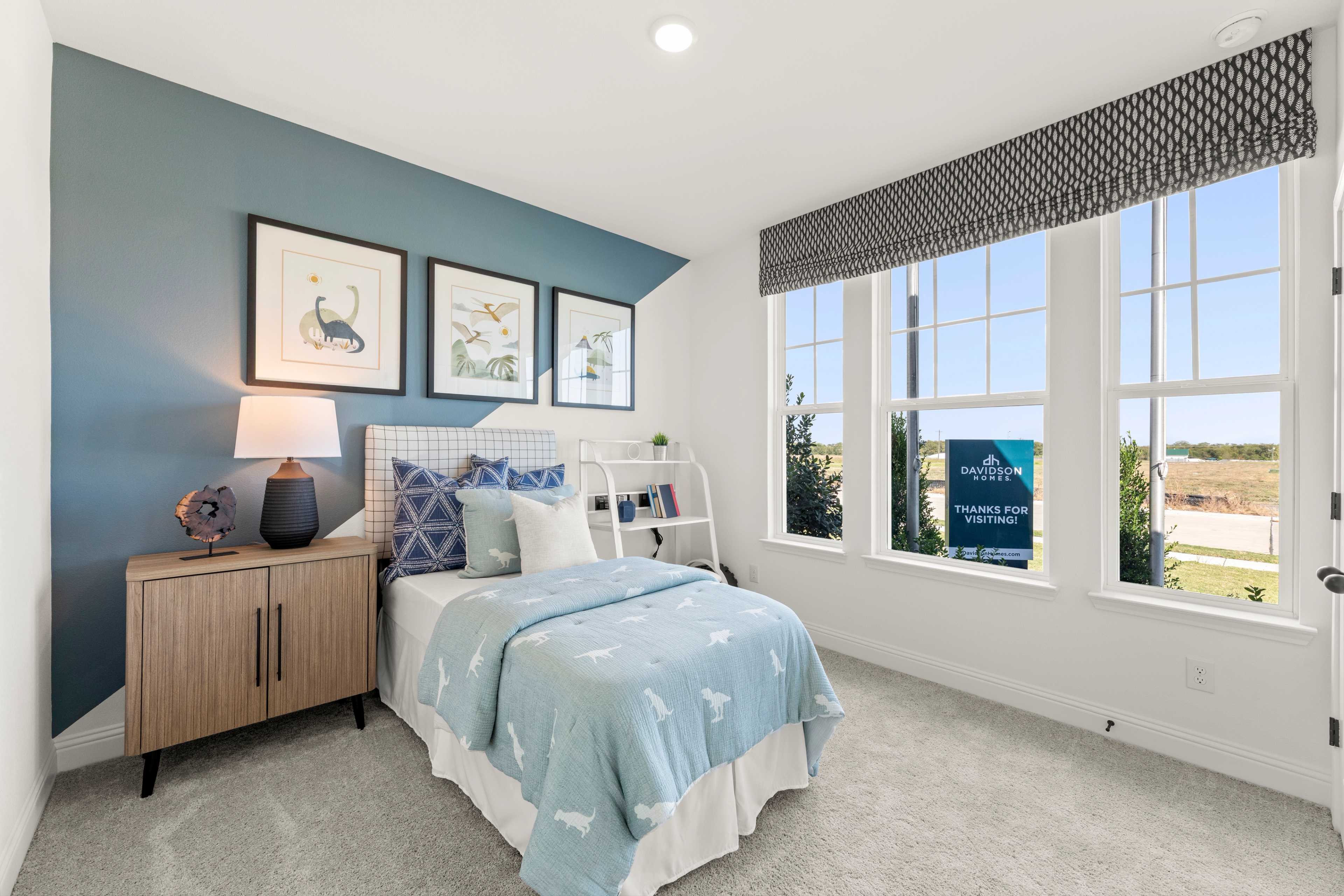 Cozy bedroom at Meadow Ridge Estates in Josephine TX with teal accent wall, blue bedding, and large windows overlooking Davidson Homes community