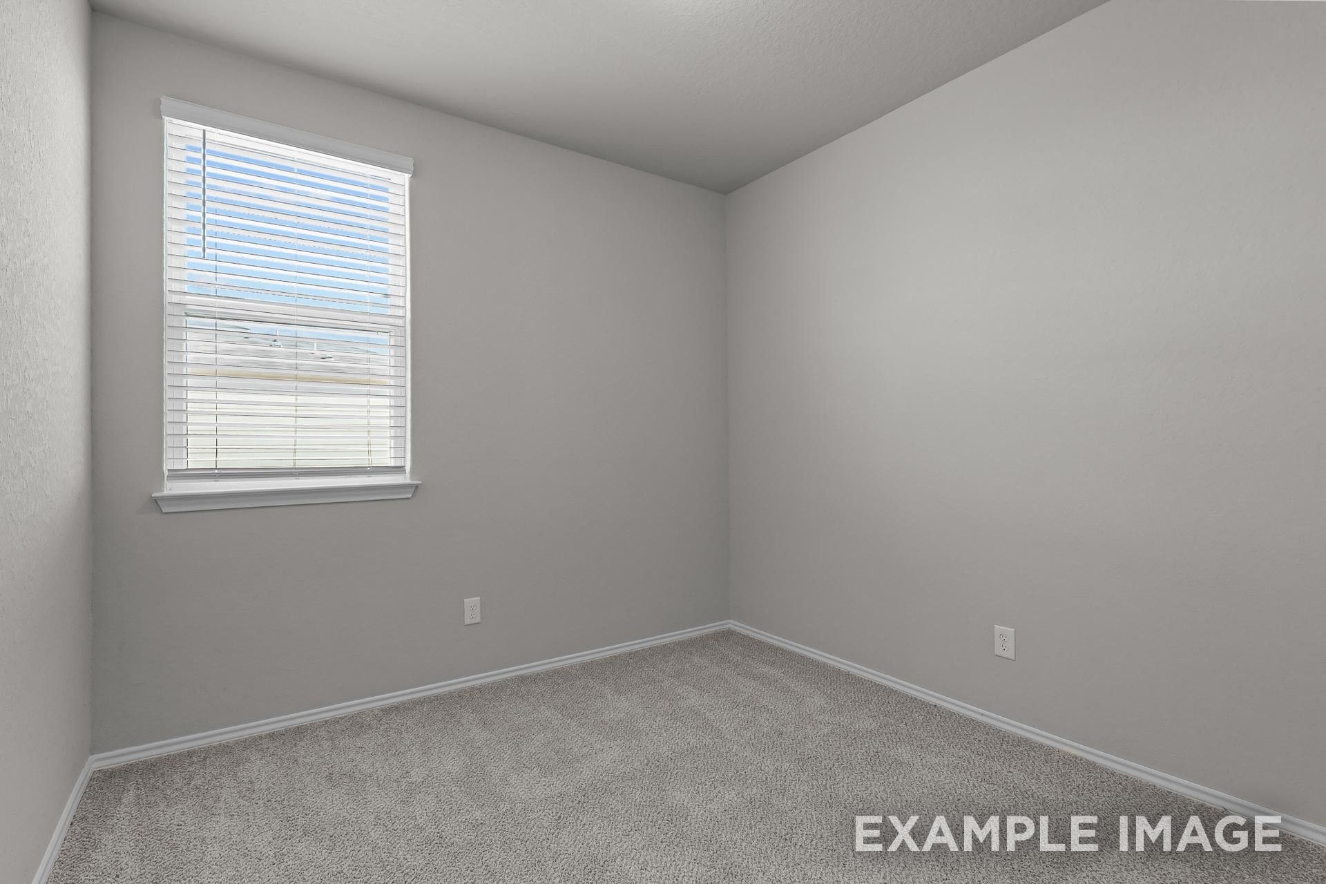 Bright secondary bedroom with neutral carpet and window in The Colorado G floor plan by Davidson Homes in Heartland, TX.