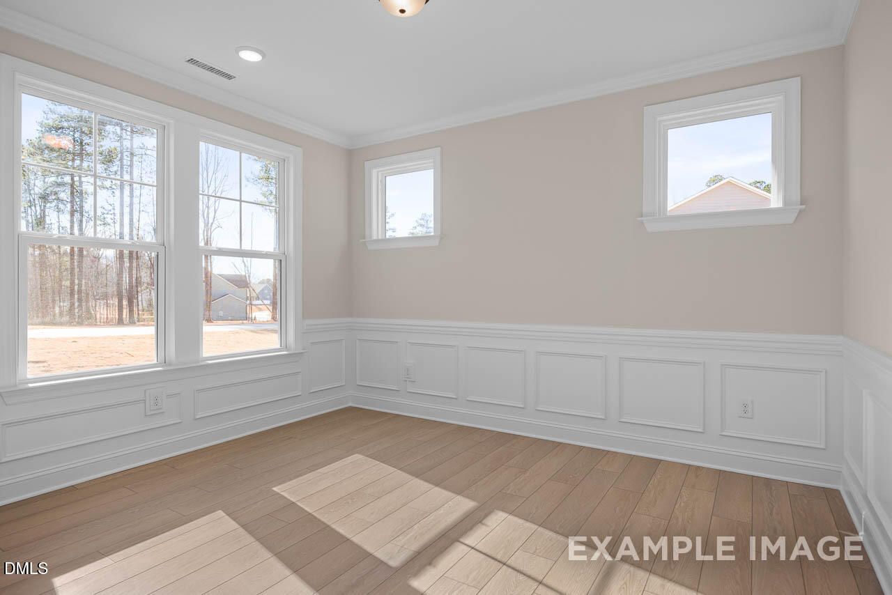 Bright bedroom with hardwood floors, wainscoting, and large windows in Davidson Homes Crawford D, Tobacco Road, Angier NC