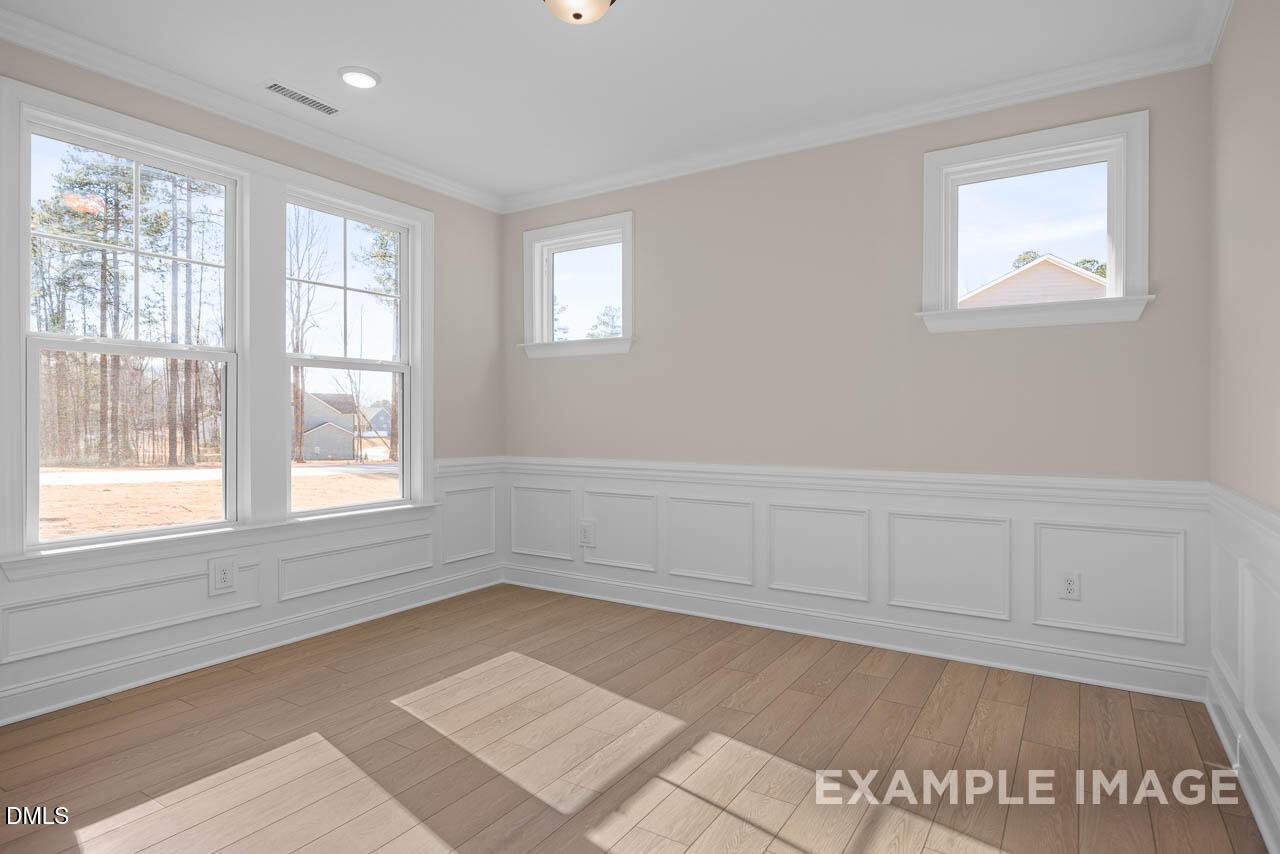 Bright bedroom with hardwood floors, wainscoting, and large windows in Davidson Homes Crawford D, Tobacco Road, Angier NC