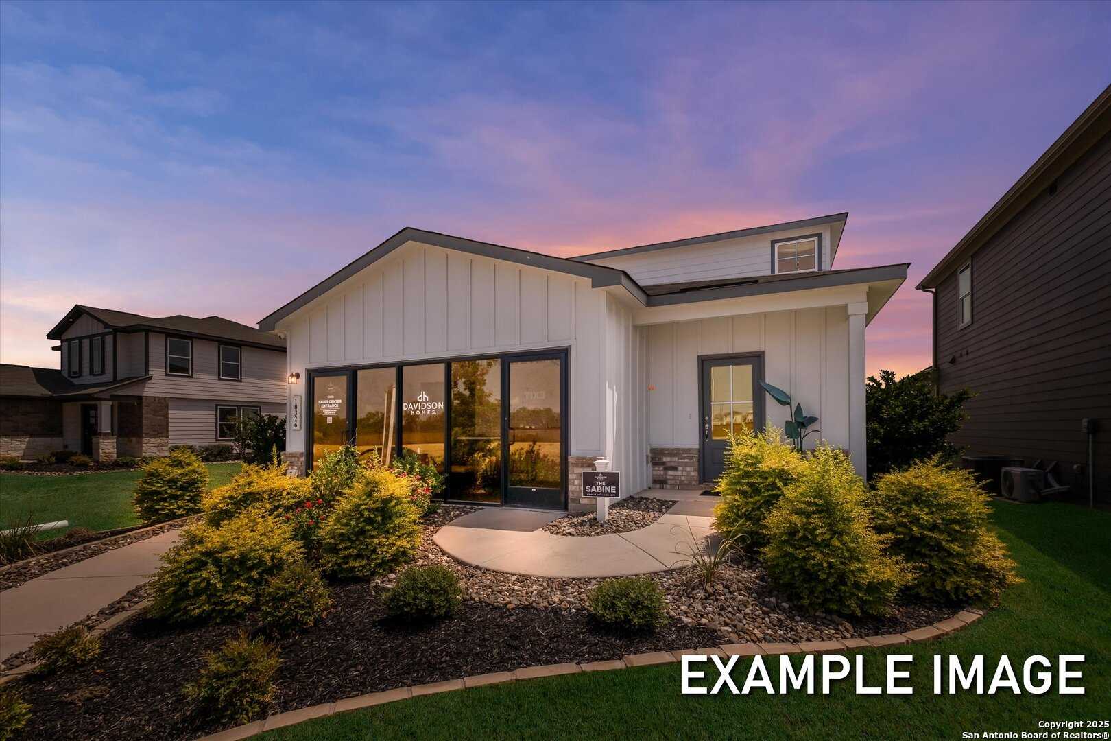 Modern Sabine B two-story home exterior with large windows, garage, and landscaped yard at dusk in Agave, San Antonio, Texas