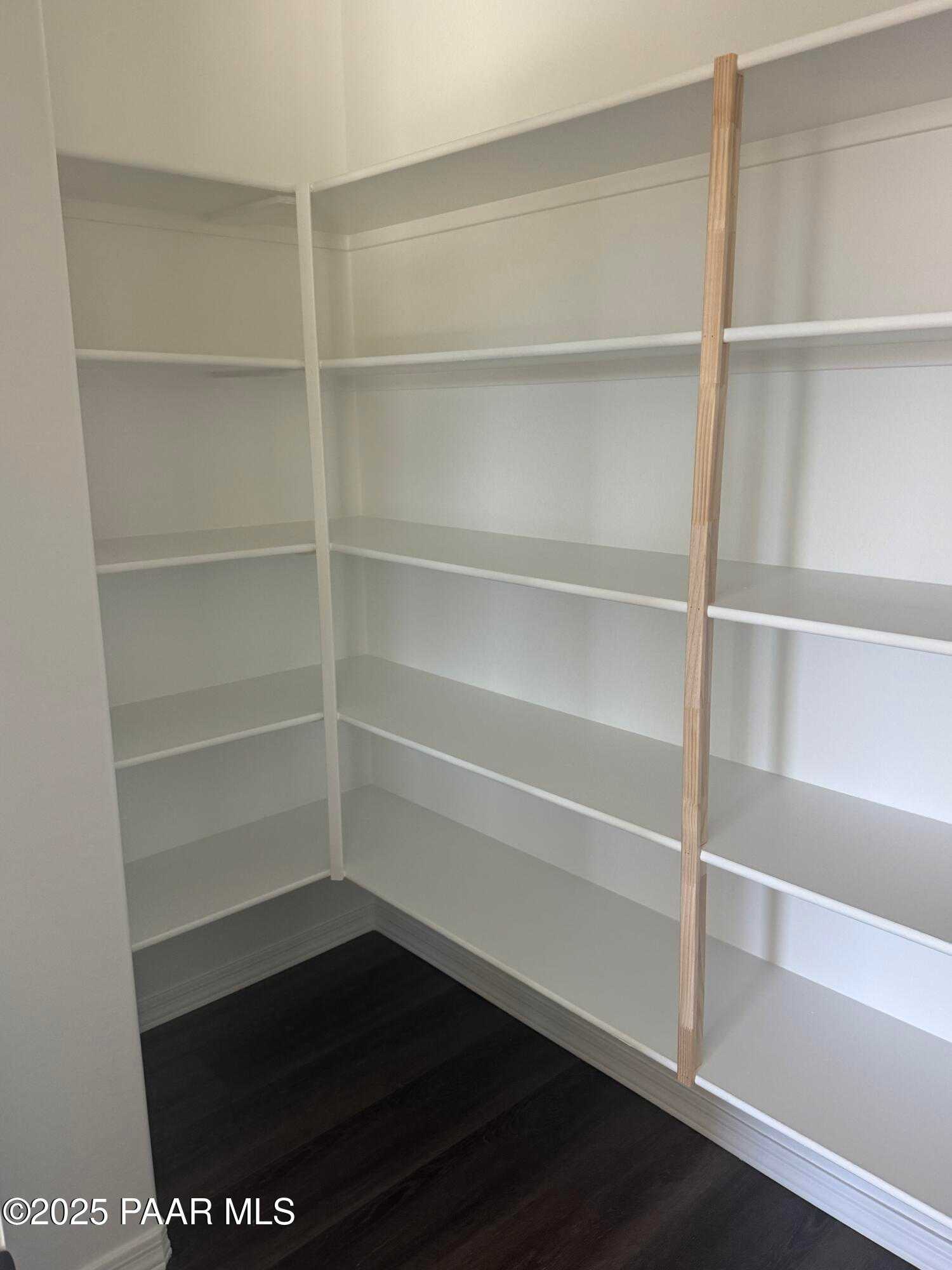 Bright corner walk-in pantry with white shelving and wooden beam in Davidson Homes The Monarch E, Prescott Arizona