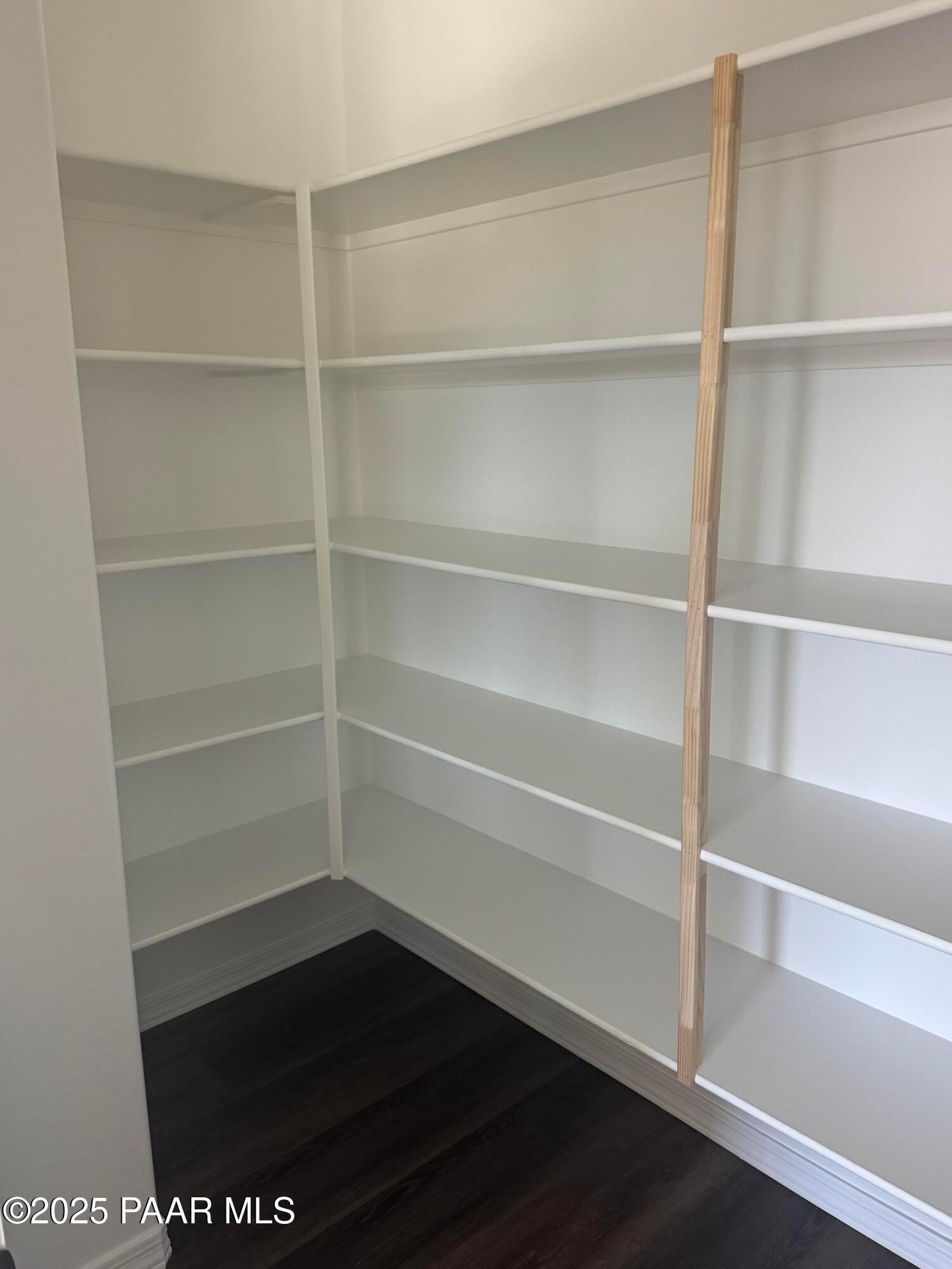 Bright corner walk-in pantry with white shelving and wooden beam in Davidson Homes The Monarch E, Prescott Arizona