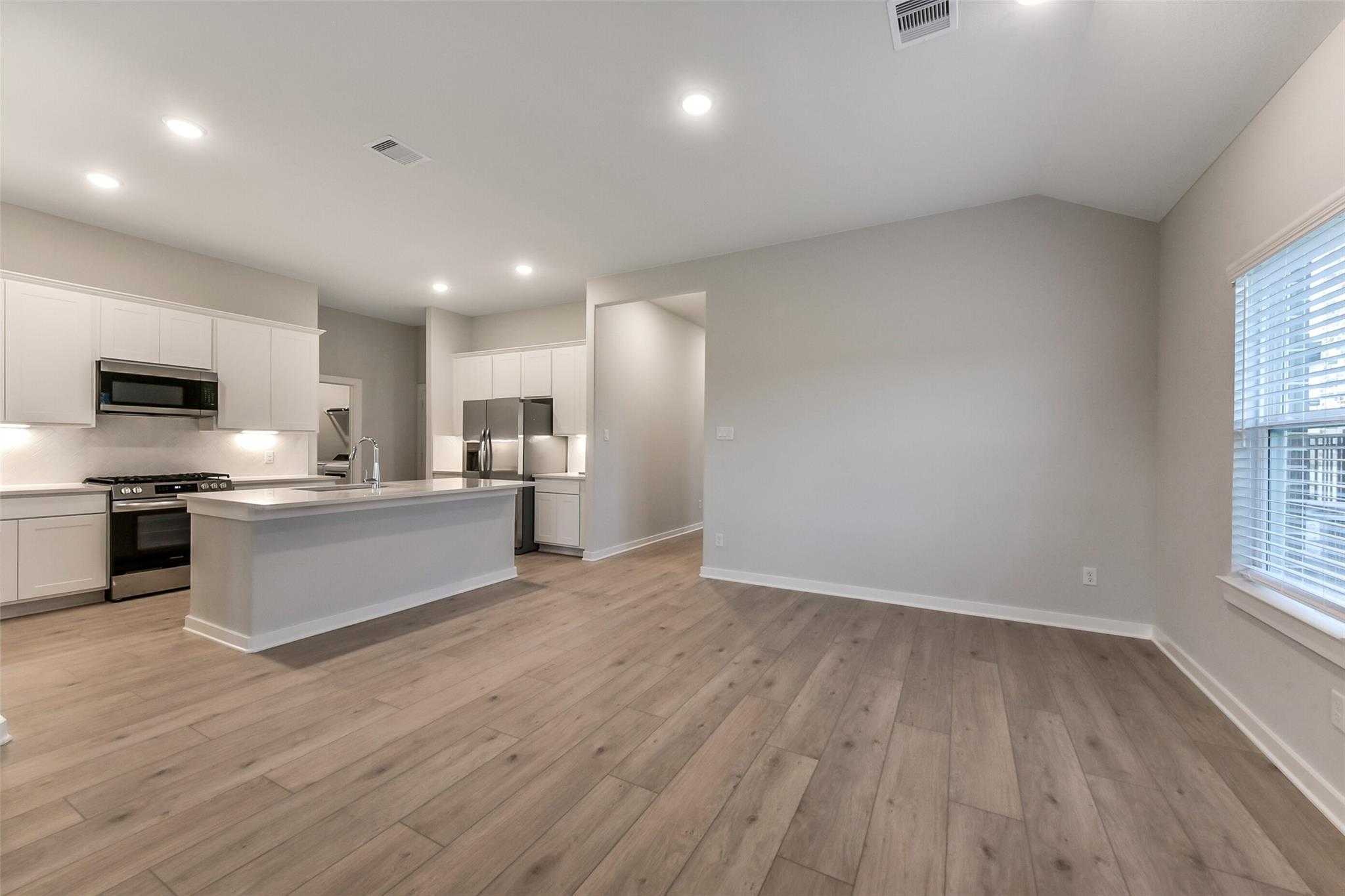 Modern open-concept kitchen with white cabinets, stainless appliances, and island in Davidson Homes The Laguna B, Katy, Texas