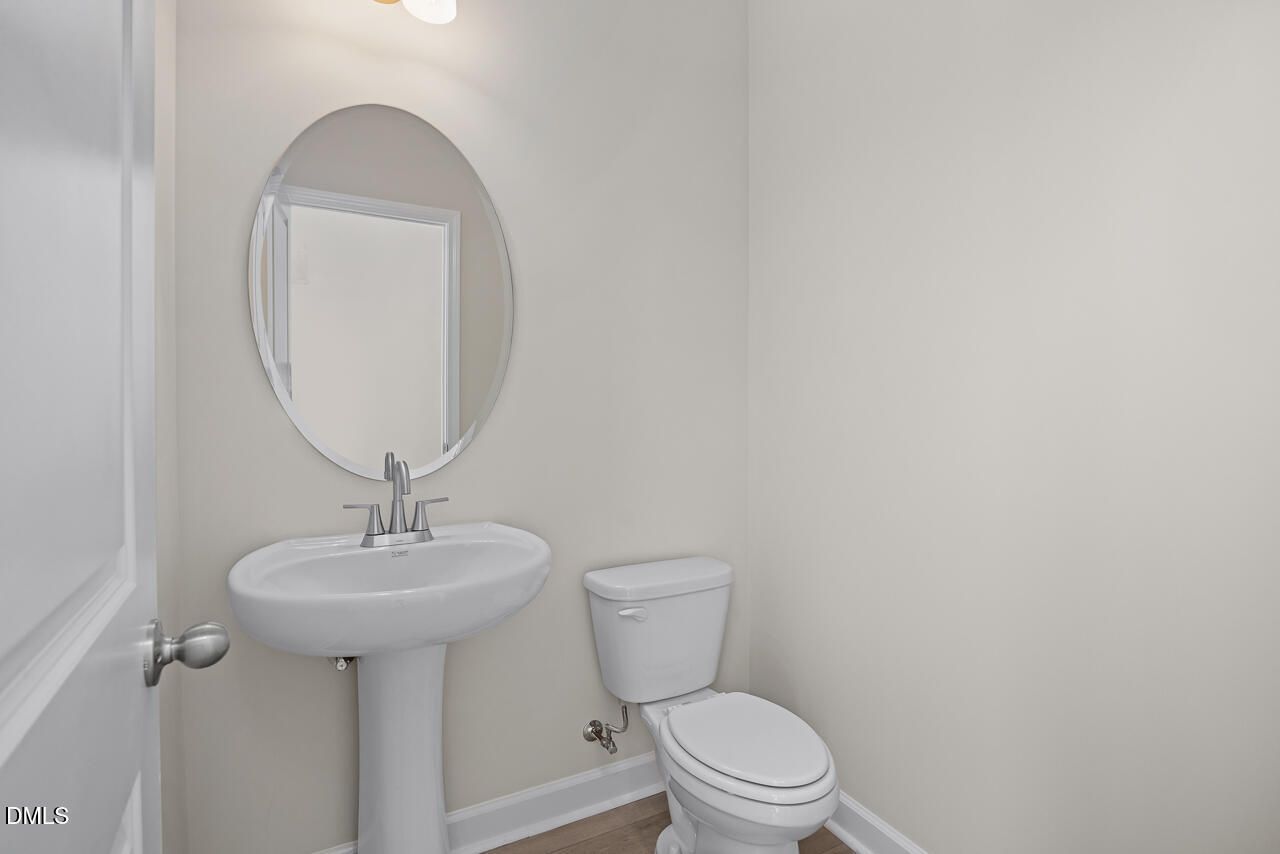Modern half bathroom with pedestal sink and oval mirror in The Mitchell Interior floor plan at Camden Park, Knightdale, NC.