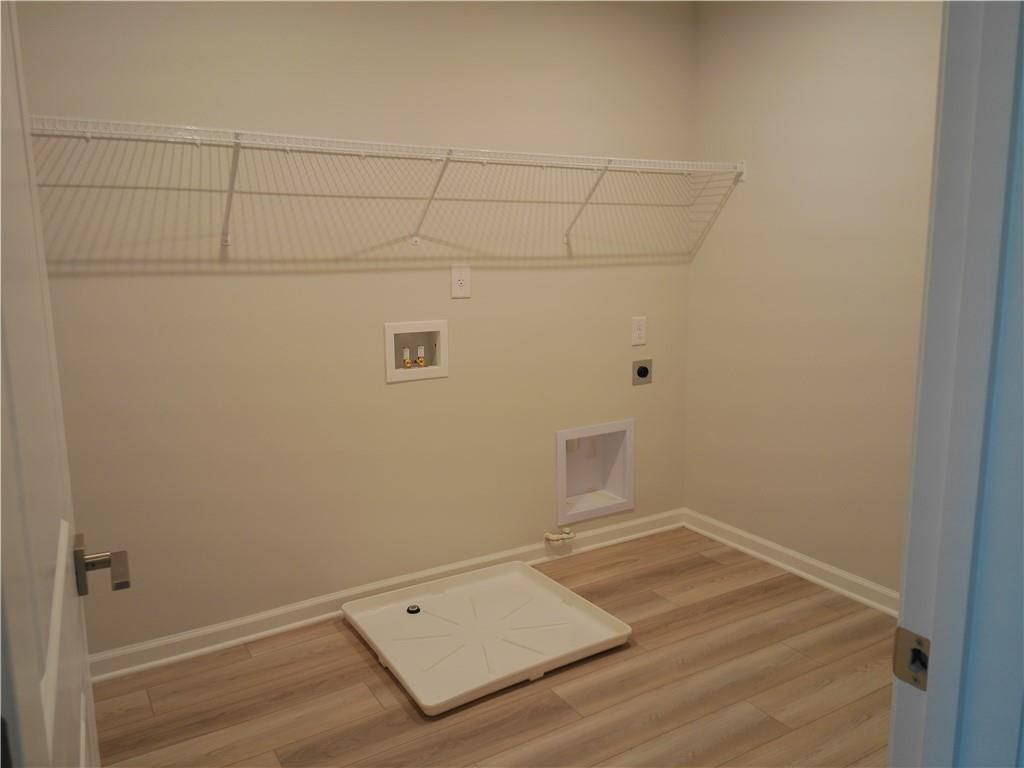 Functional laundry room with wire shelving, washer/dryer hookups, and luxury vinyl plank flooring in Davidson Homes The Marion C, Winder, Georgia