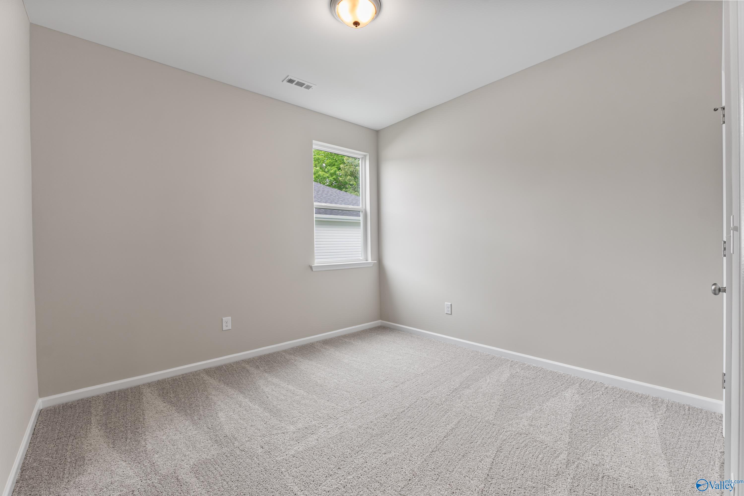 Bright secondary bedroom with neutral walls, large window, and plush carpet in Davidson Homes The Phoenix, Fayetteville, TN