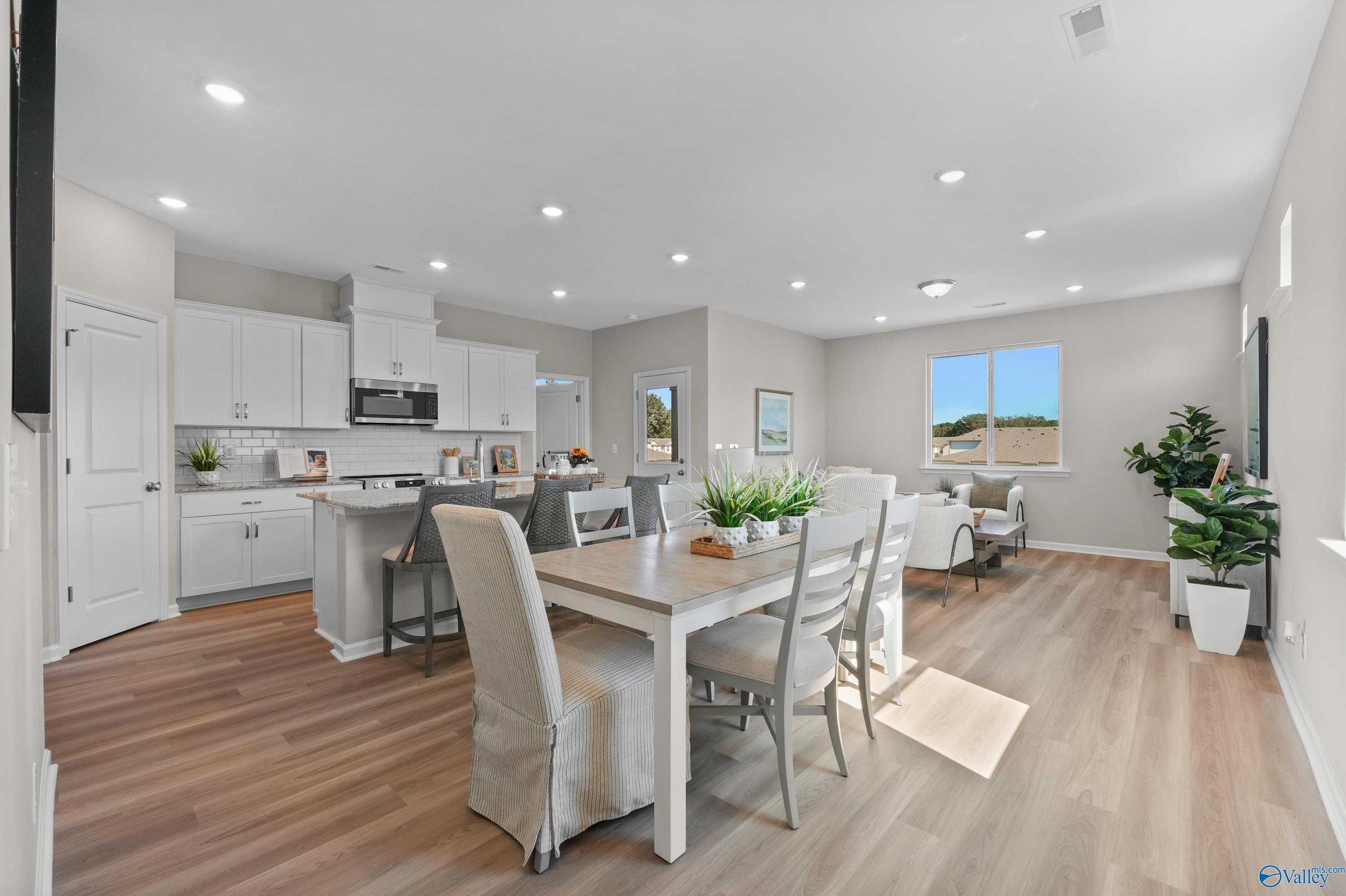 Bright open-concept kitchen and dining with white cabinets, island, hardwood floors in The Malibu 2-bedroom home, Madison, Alabama