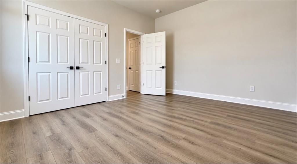 Spacious bedroom with luxury vinyl plank flooring and double-door closet in Davidson Homes The Harrison H, Wehunt Meadows, Hoschton