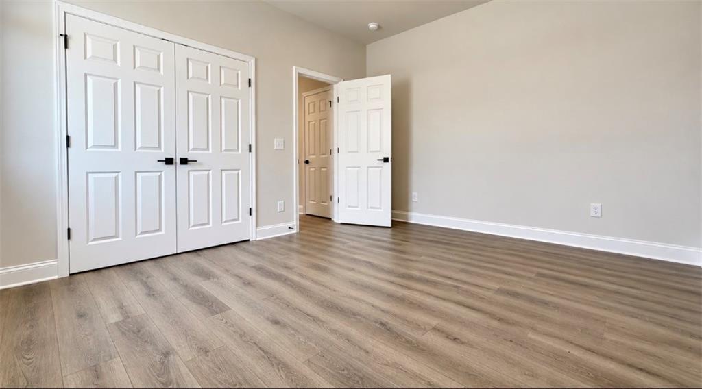 Spacious bedroom with luxury vinyl plank flooring and double-door closet in Davidson Homes The Harrison H, Wehunt Meadows, Hoschton