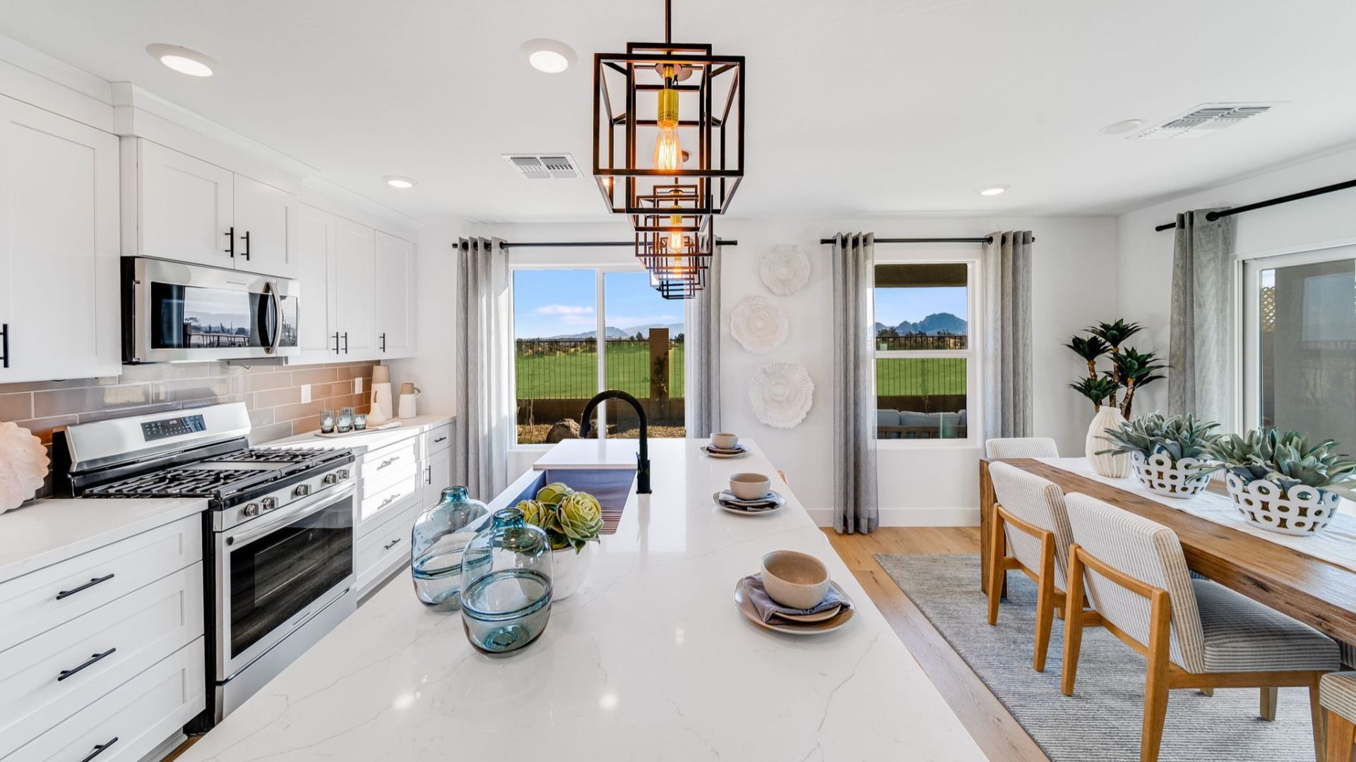 Spacious white kitchen with island, stainless appliances, and dining area at Senator Cottages in Prescott AZ, scenic field views