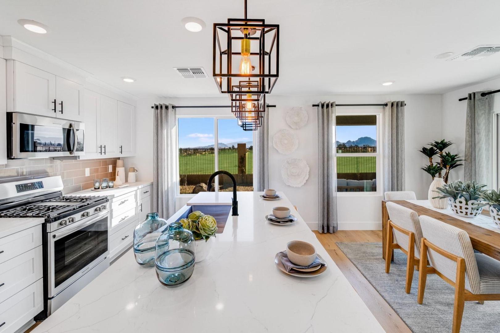 Spacious white kitchen with island, stainless appliances, and dining area at Senator Cottages in Prescott AZ, scenic field views