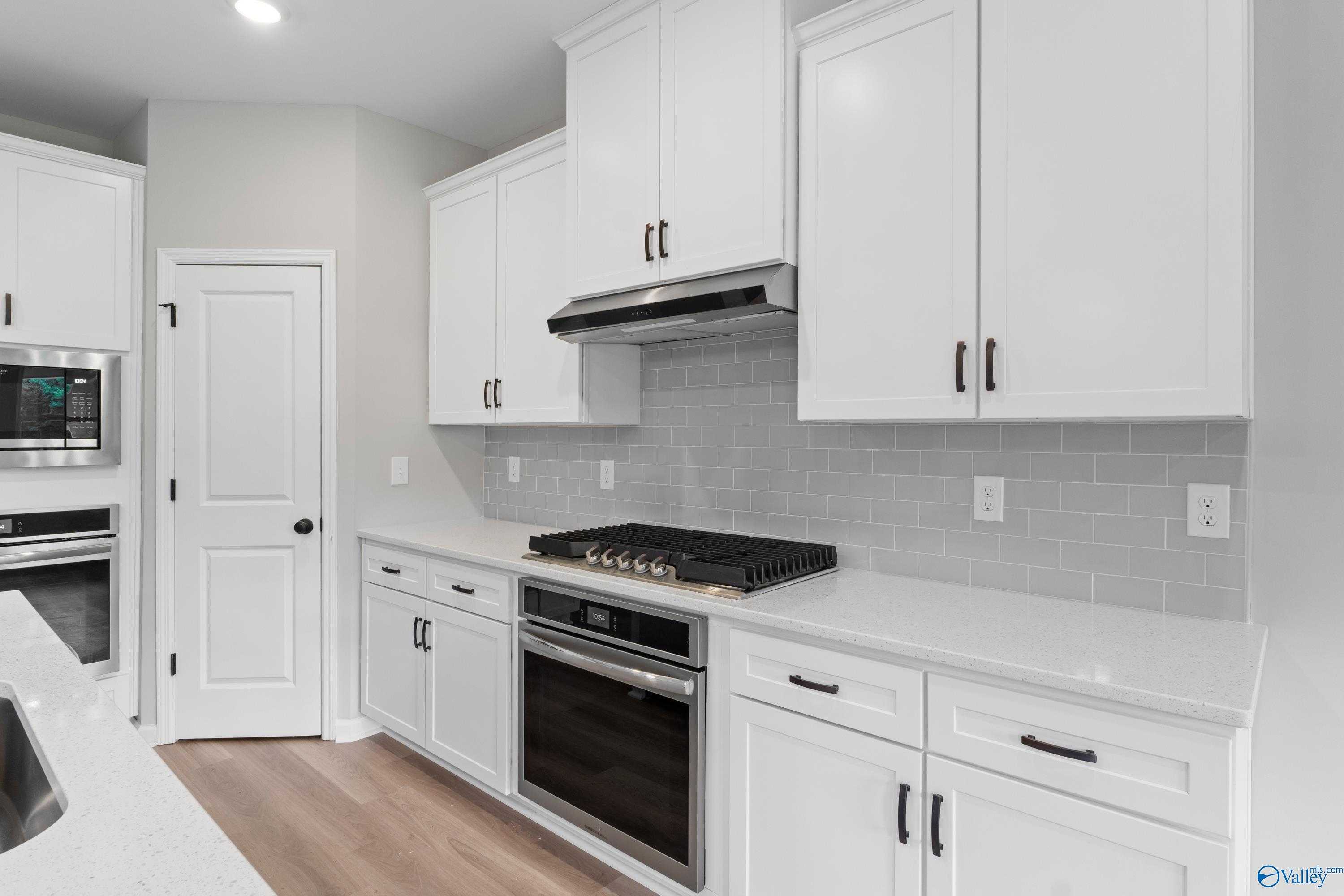 Modern white kitchen with shaker cabinets, stainless steel range and oven, gray subway tile backsplash in Davidson Homes The Dorado, Huntsville AL
