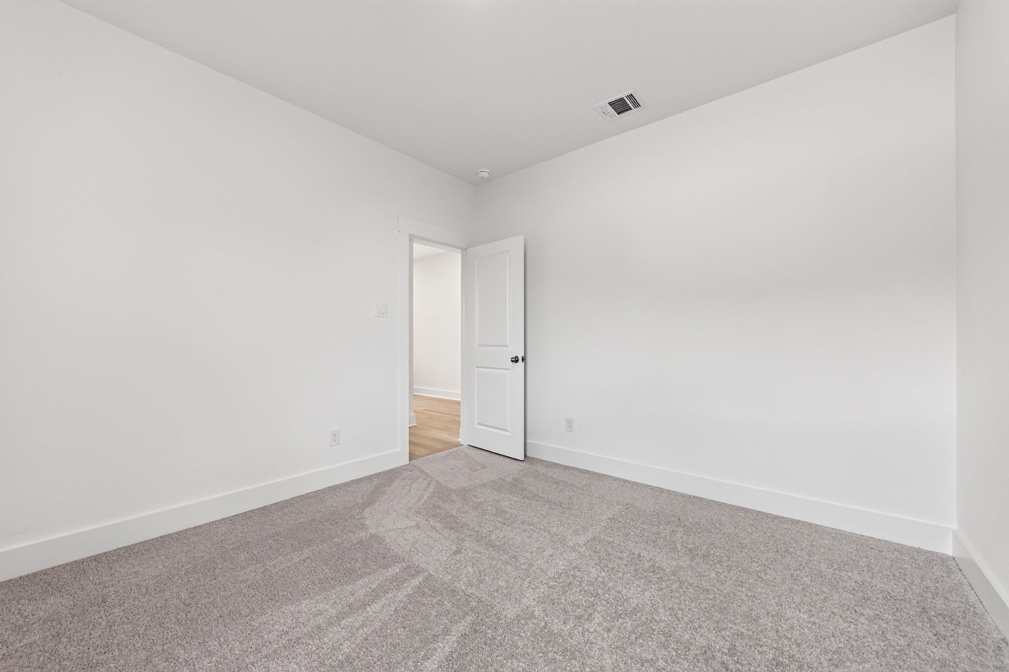Empty bedroom with white walls, gray carpet, and open door in Davidson Homes The Holly F floor plan at Meadow Ridge Estates, Josephine, Texas