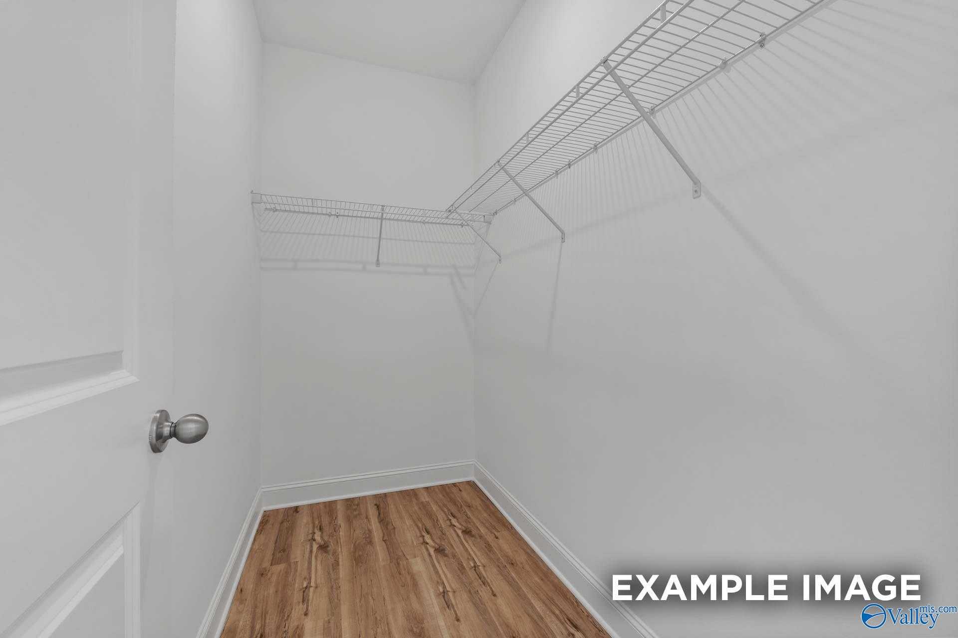 Spacious walk-in closet with wire shelving and hardwood floors in Davidson Homes The Butler, Toney, Alabama