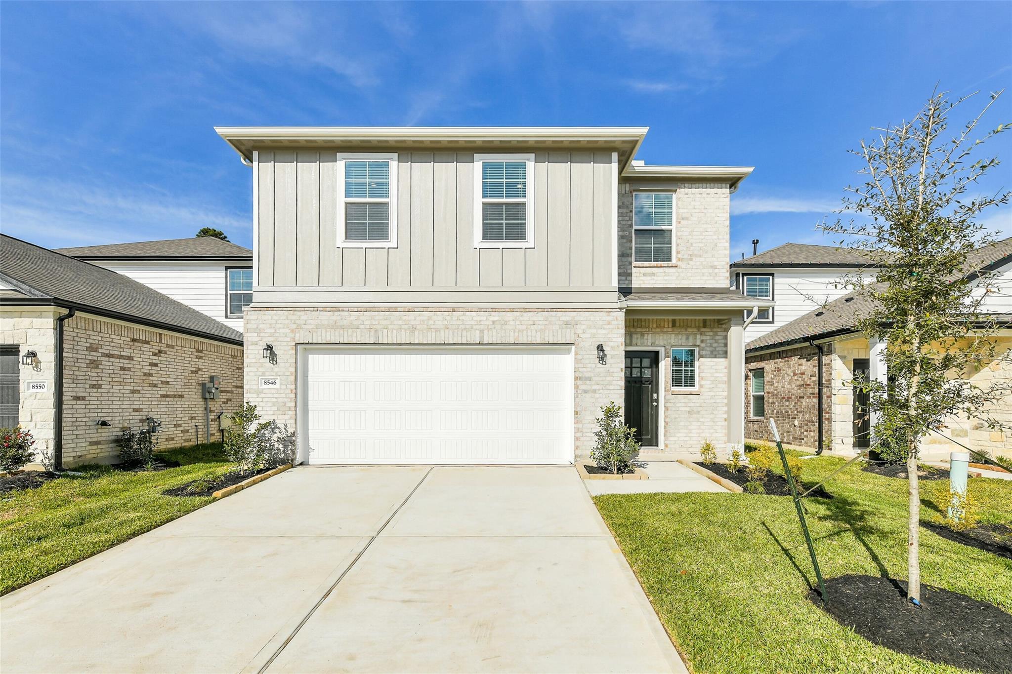 Modern 2-story brick home with 2-car garage, driveway, and lush lawn in Lakes at Black Oak, Magnolia, Texas by Davidson Homes