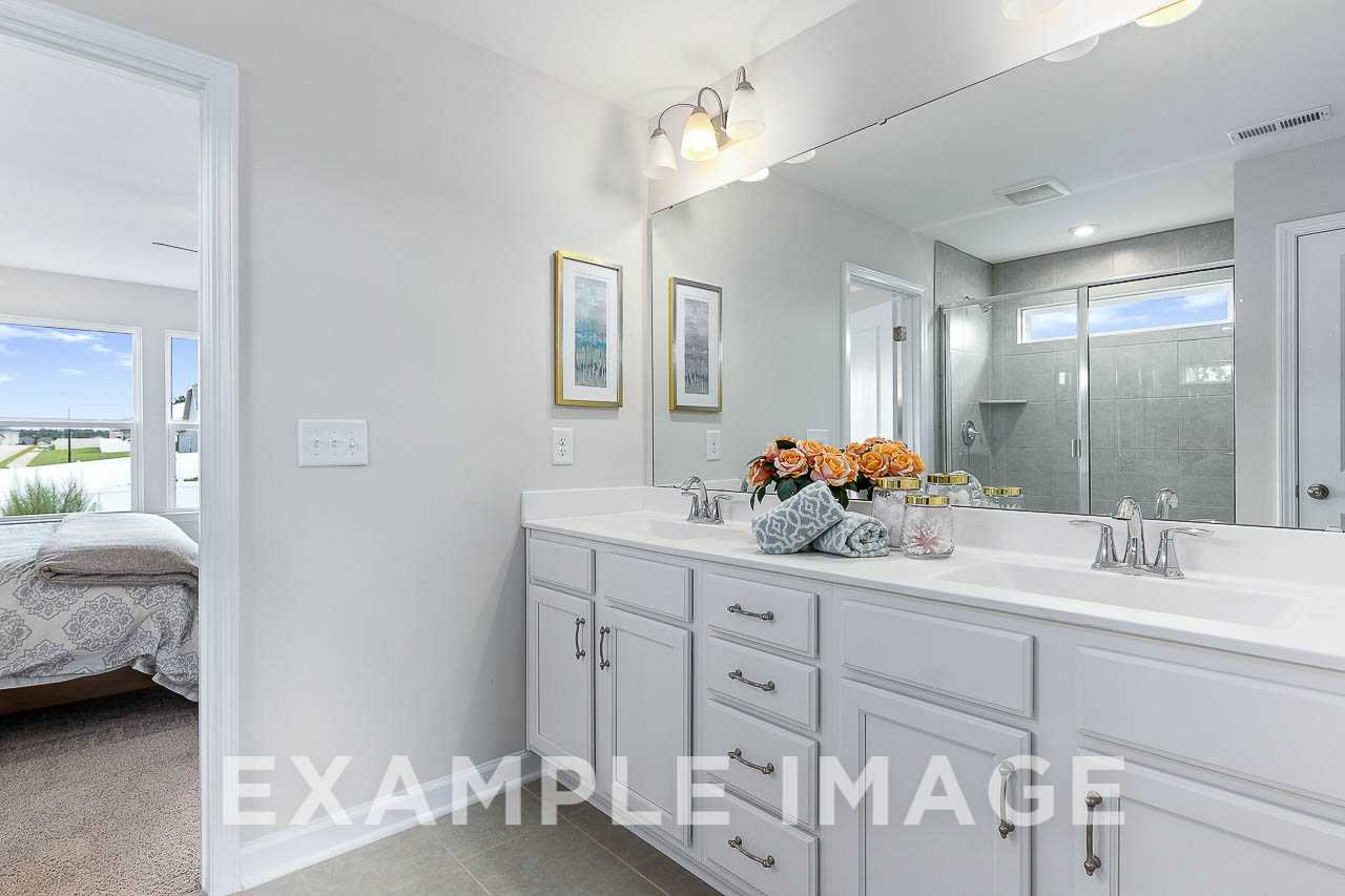 Spacious master bathroom in The Willow C home with double vanity, large mirror, walk-in shower, and bedroom view
