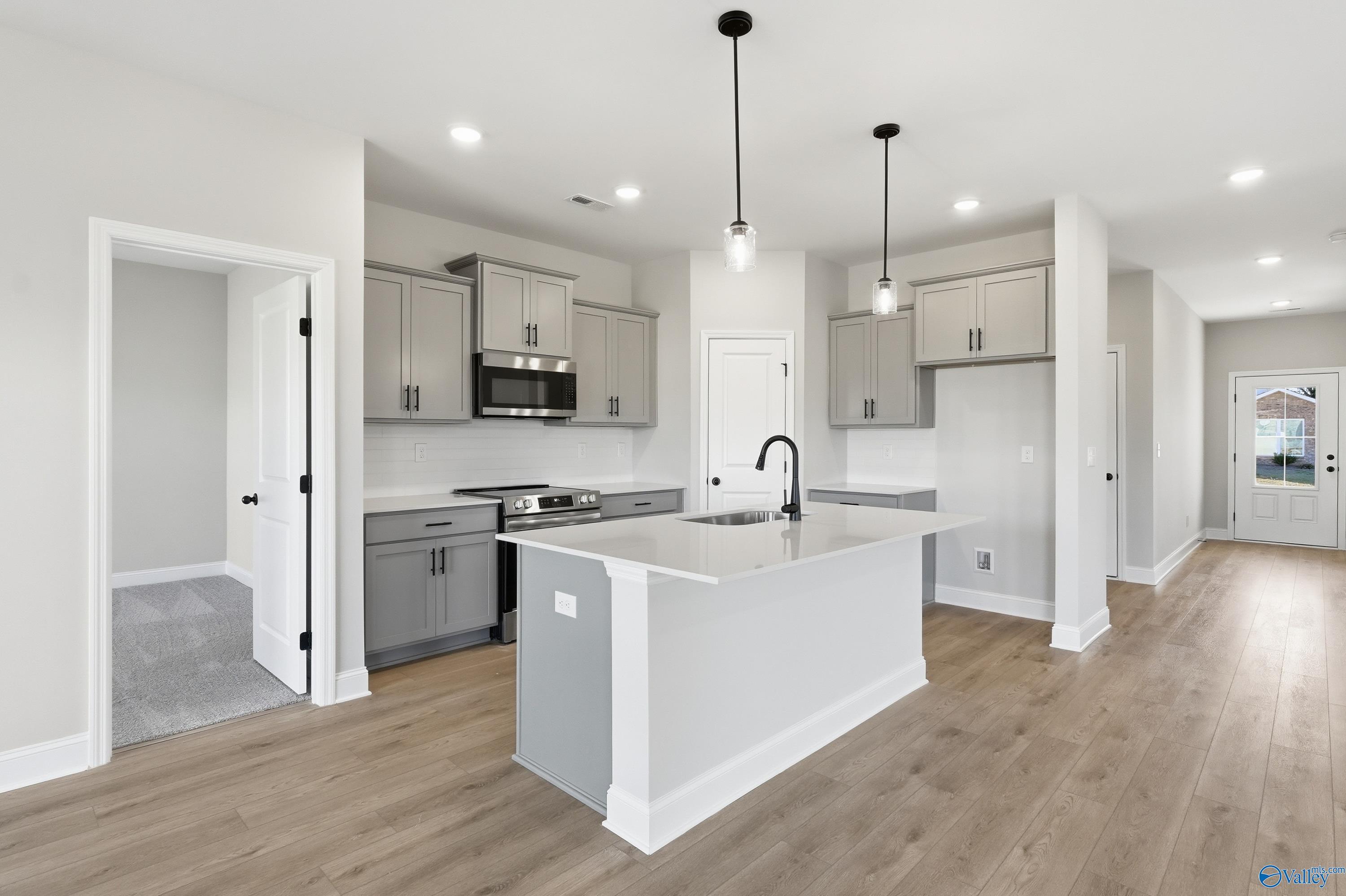 Modern kitchen featuring white shaker cabinets, gray island with quartz countertop, stainless appliances in Davidson Homes The Franklin C, New Market, AL