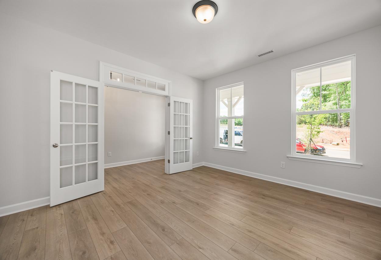 Bright flex room with French doors and wood-look flooring in The Birch II home design by Davidson Homes.