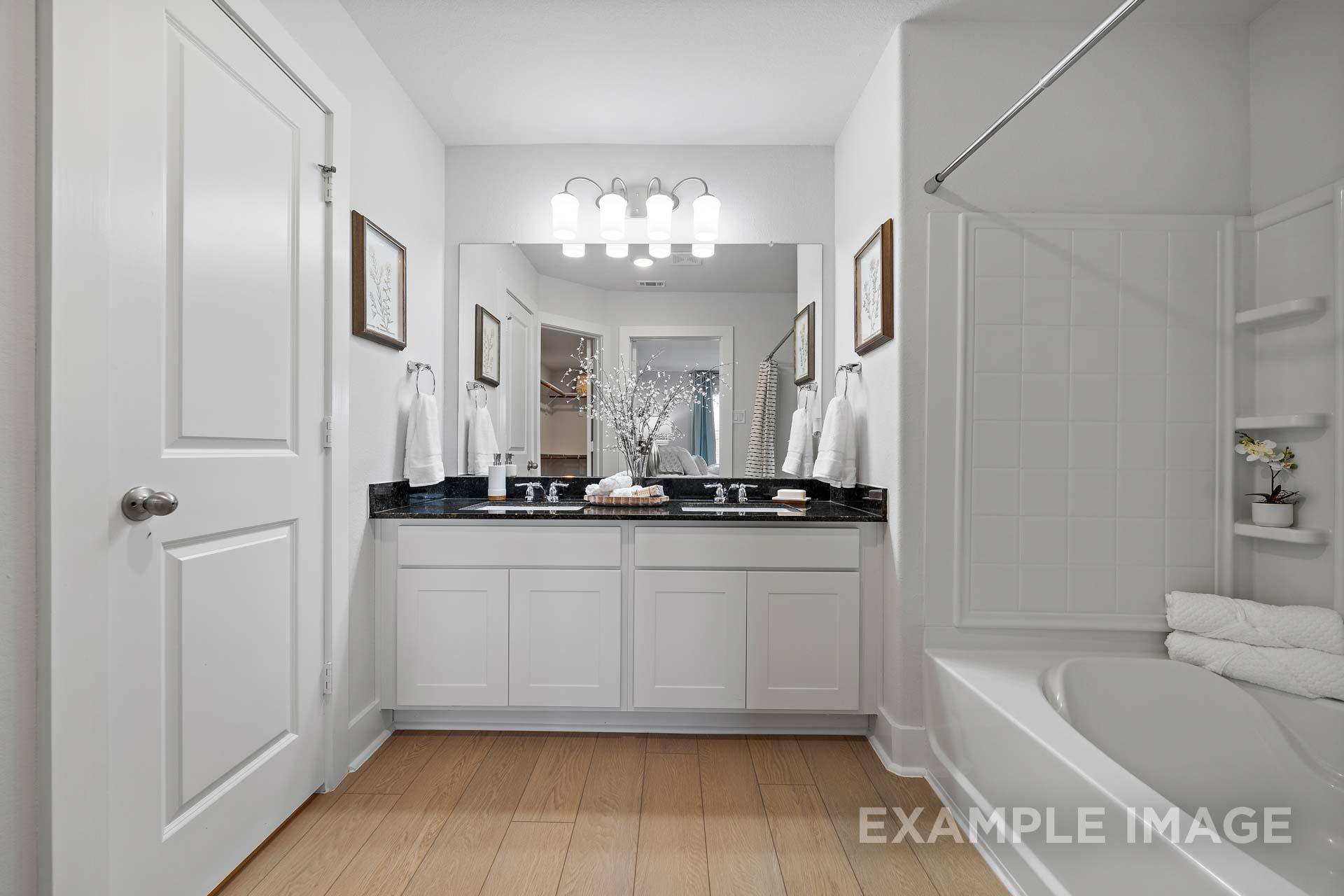 Spacious master bathroom in The Rose B with double vanity, black granite countertop, soaking tub, and walk-in shower