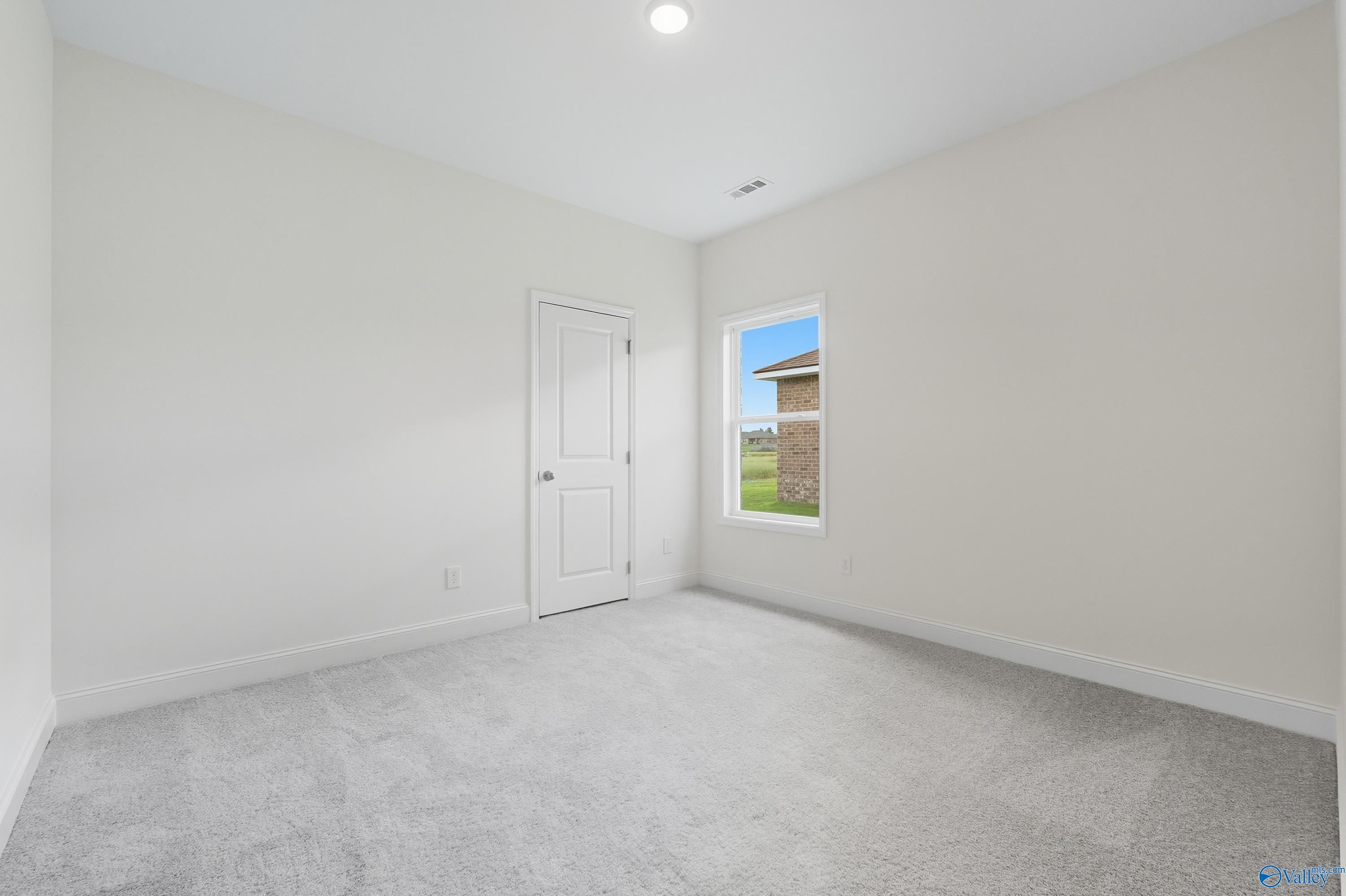 Bright secondary bedroom with white walls, carpeted floor and window view in The Everett 4-bedroom home, Meridianville, Alabama