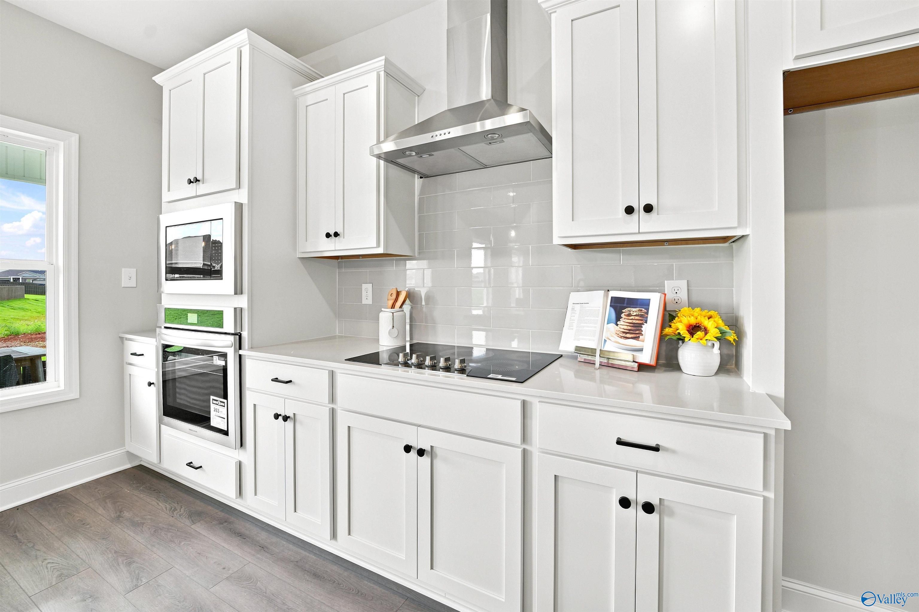 Modern white kitchen with stainless appliances and subway tile backsplash in The Burton B floor plan, Heritage Lakes.