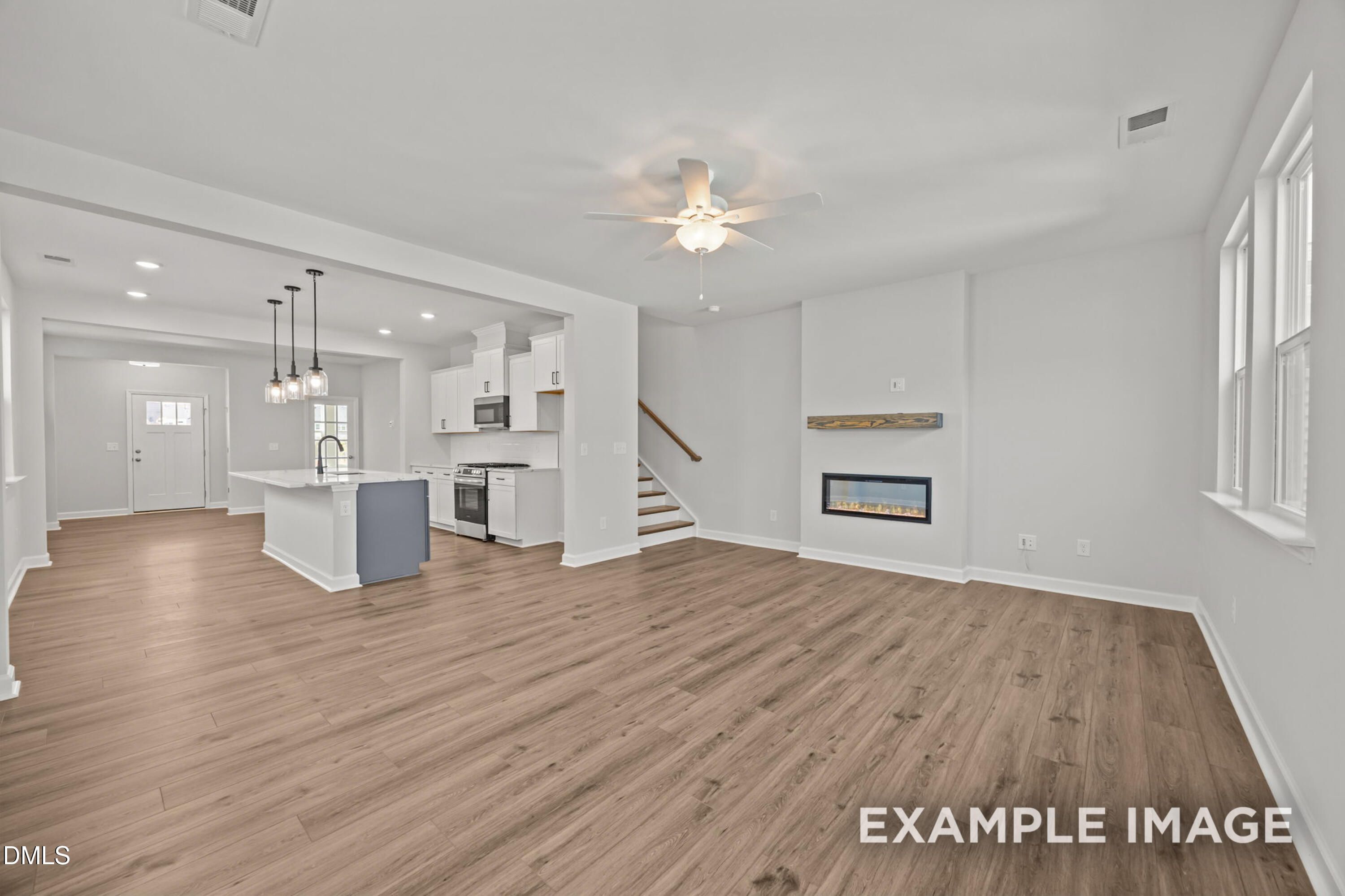 Open-concept living room and kitchen with fireplace in The Alexander B floor plan at Forestville Yard, Knightdale, NC.