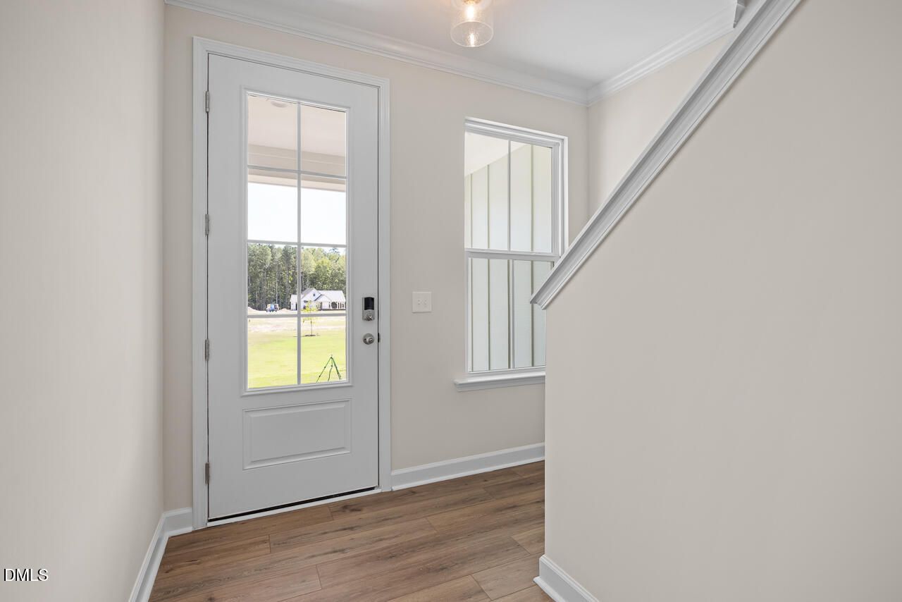 Bright foyer with glass-panel front door, hardwood floors, and staircase in Davidson Homes' The Mitchell plan, Knightdale, NC