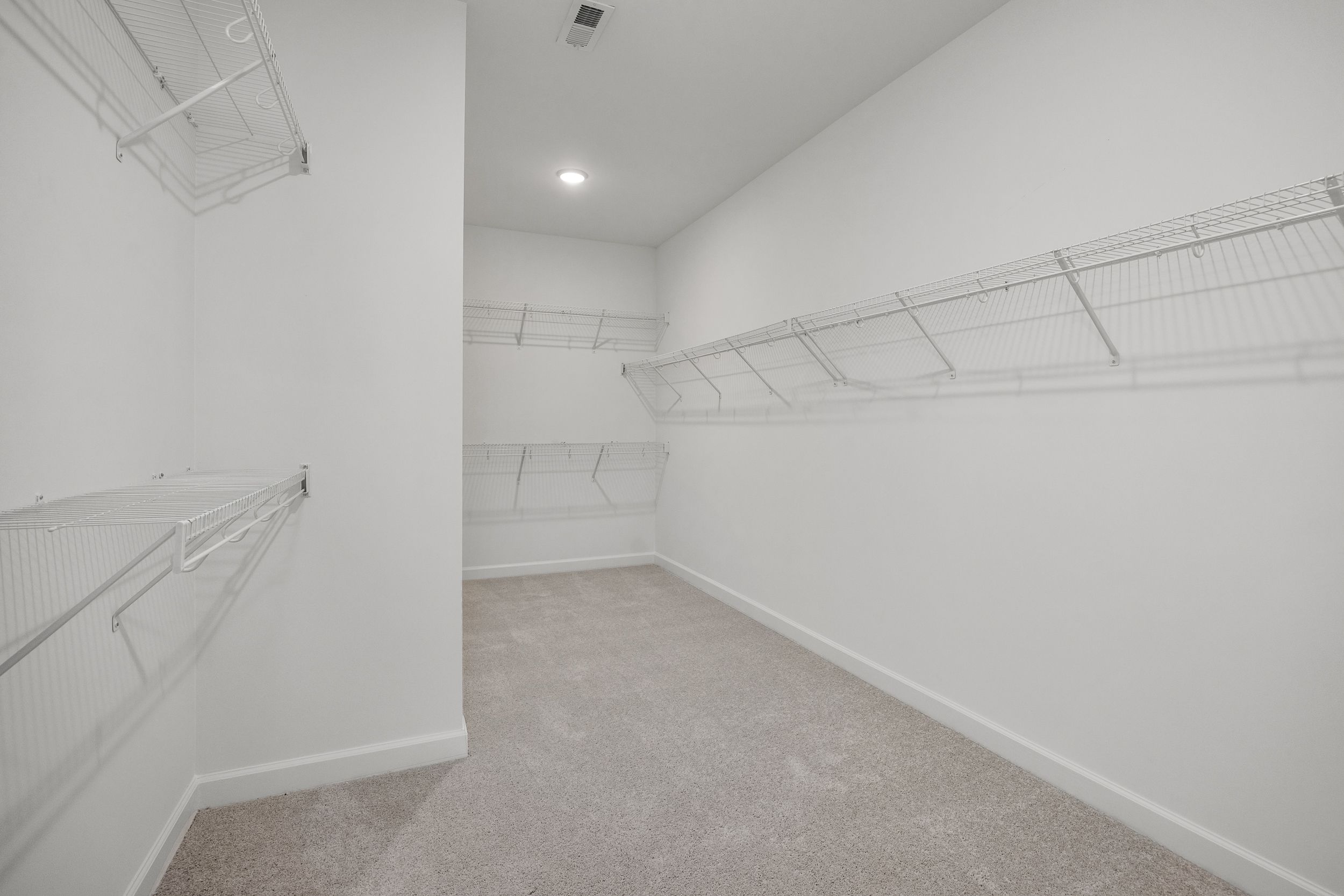 Spacious walk-in closet in The Aspen C master suite with wire shelving, white walls, and beige carpet