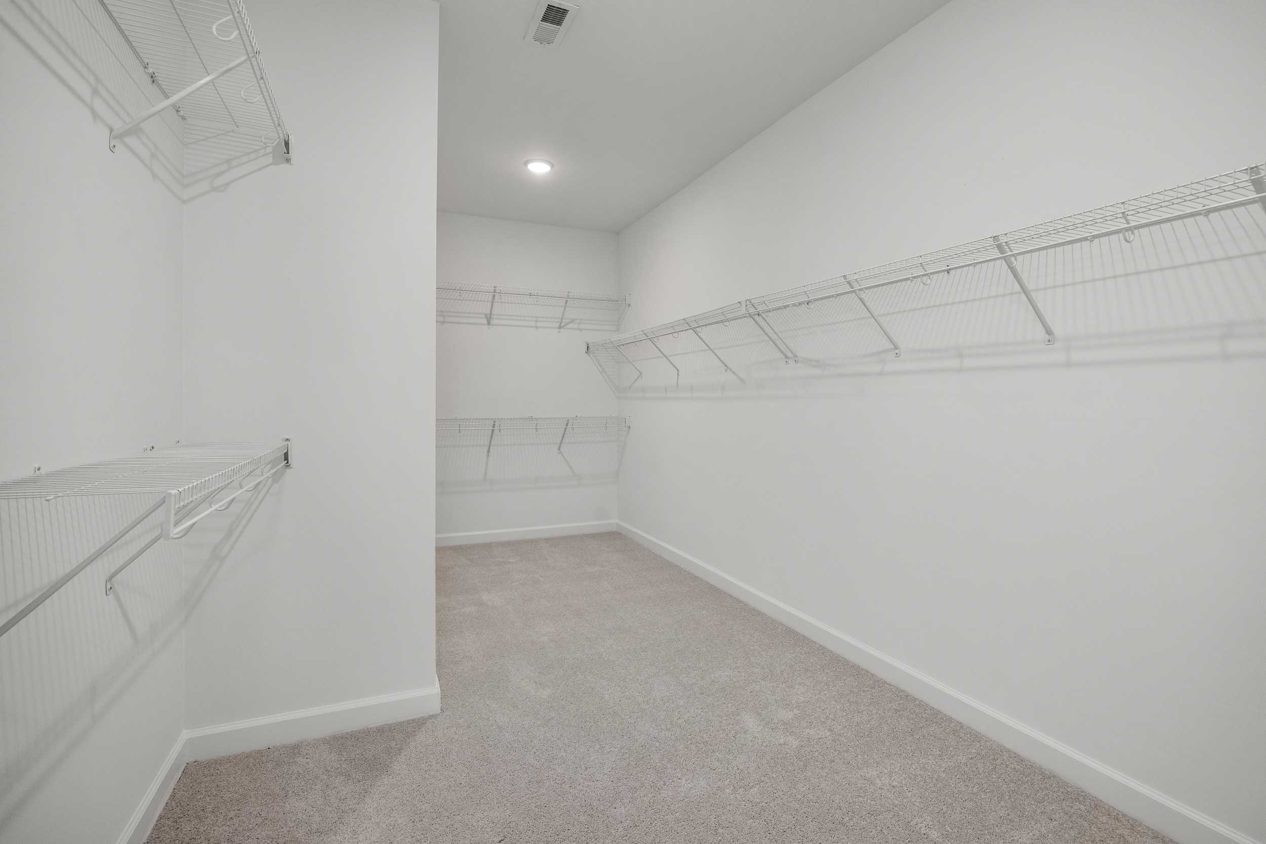 Spacious walk-in closet in The Aspen C master suite with wire shelving, white walls, and beige carpet