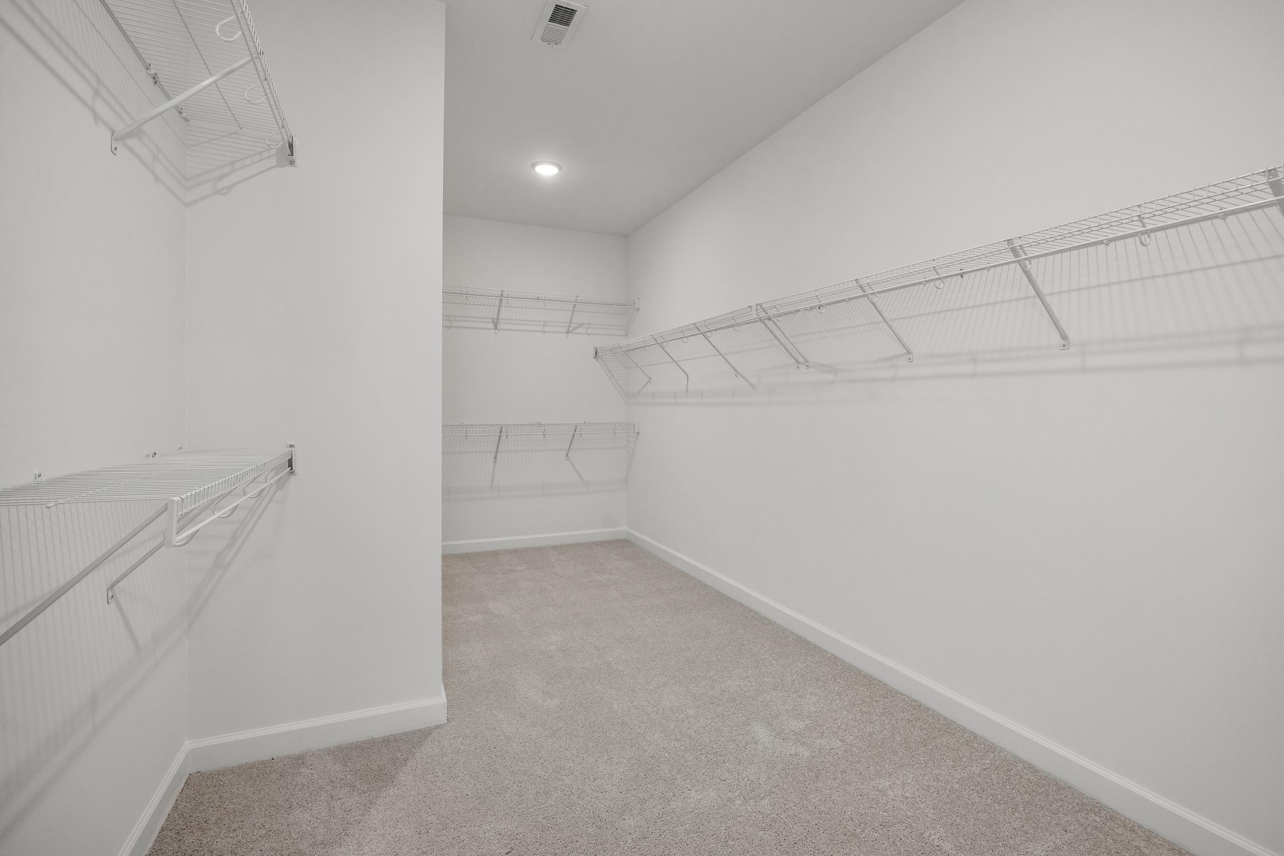 Spacious walk-in closet in The Aspen C master suite with wire shelving, white walls, and beige carpet