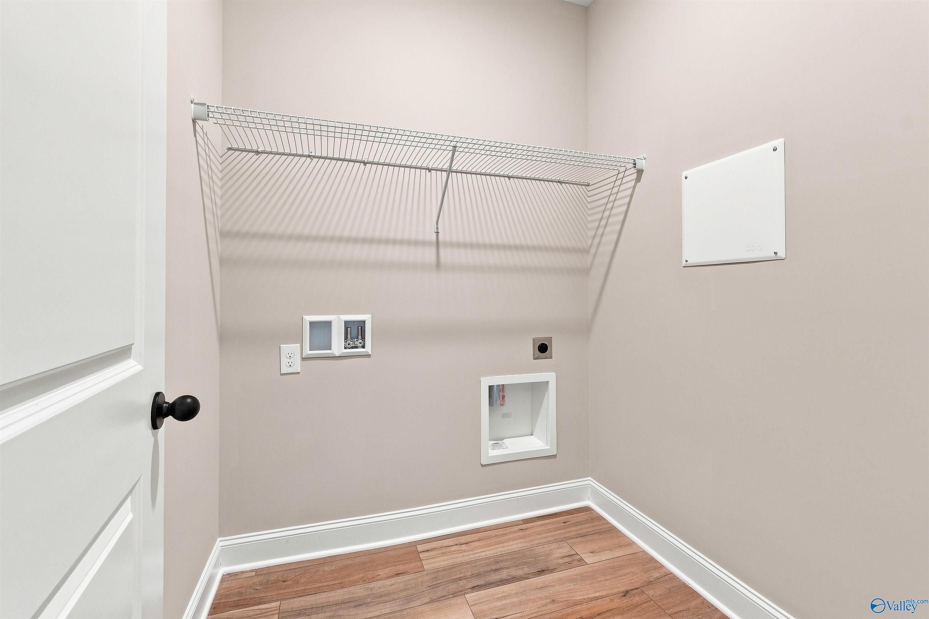 Laundry room with wire shelving, washer hookups, and wood-look flooring in Davidson Homes Franklin C plan, Toney, Alabama