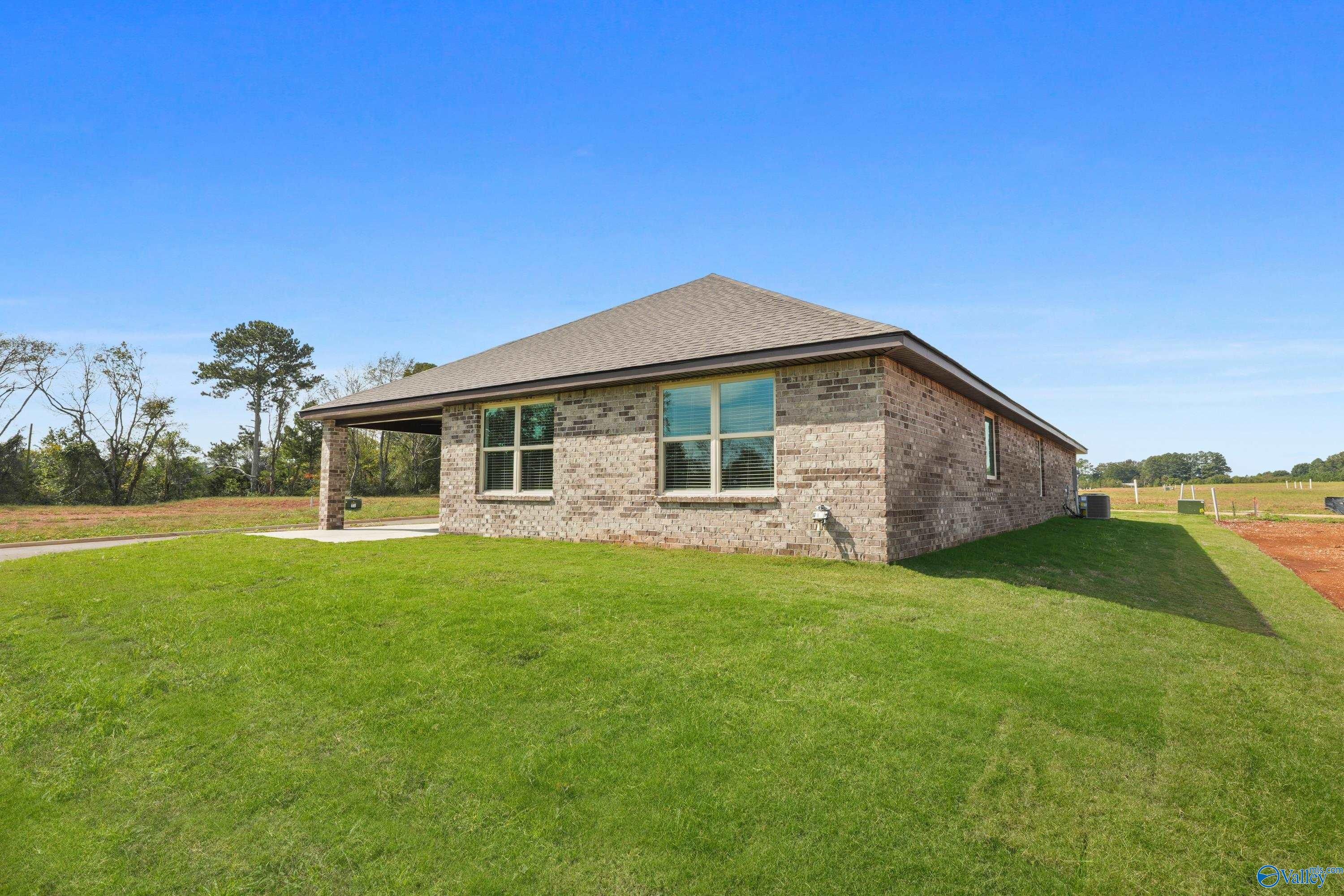 Single-story brick home with covered porch, large windows, and lush green lawn in The Meadows, Athens, Alabama by Davidson Homes