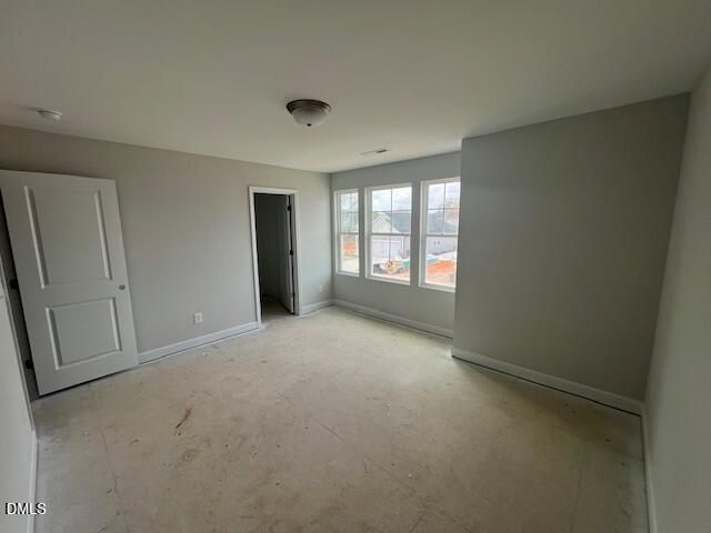 Empty upstairs bedroom featuring gray walls, large windows with natural light, and adjacent door in Davidson Homes Adalynn B, Lillington, NC