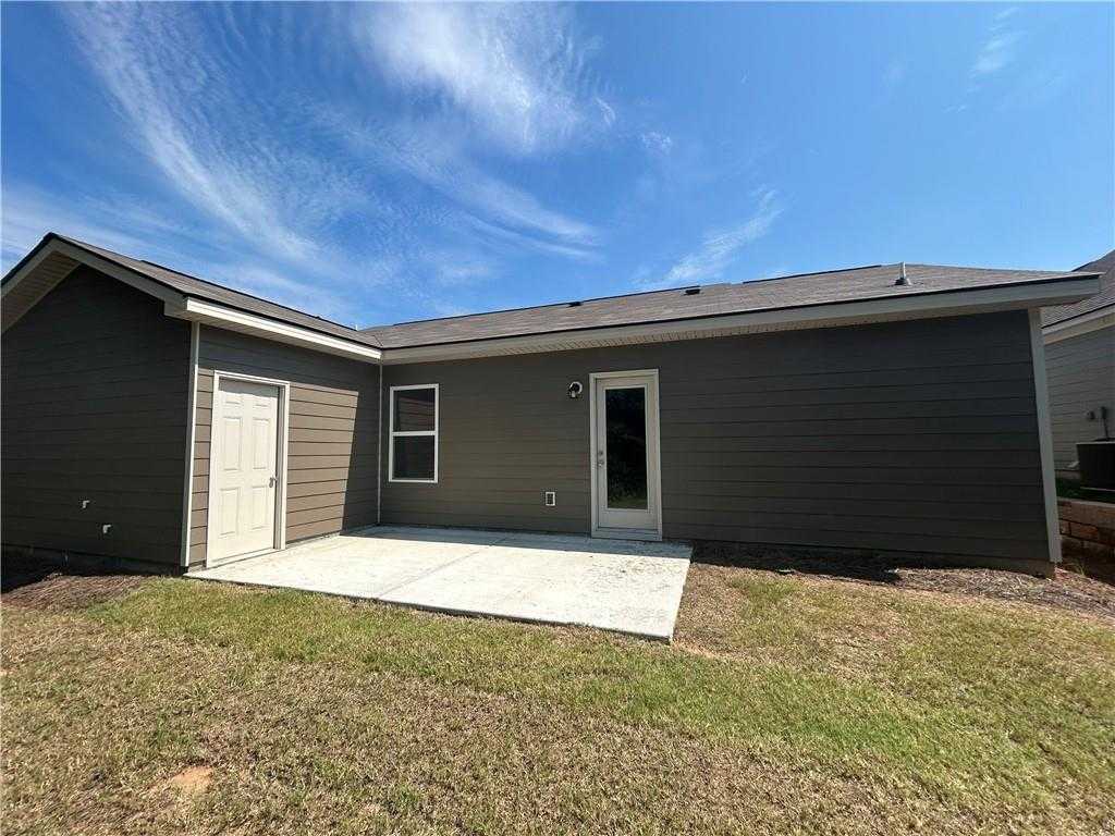 Covered back patio with sliding door on gray-sided 1-story home, grassy yard in Summer Vineyard, Phenix City, Alabama