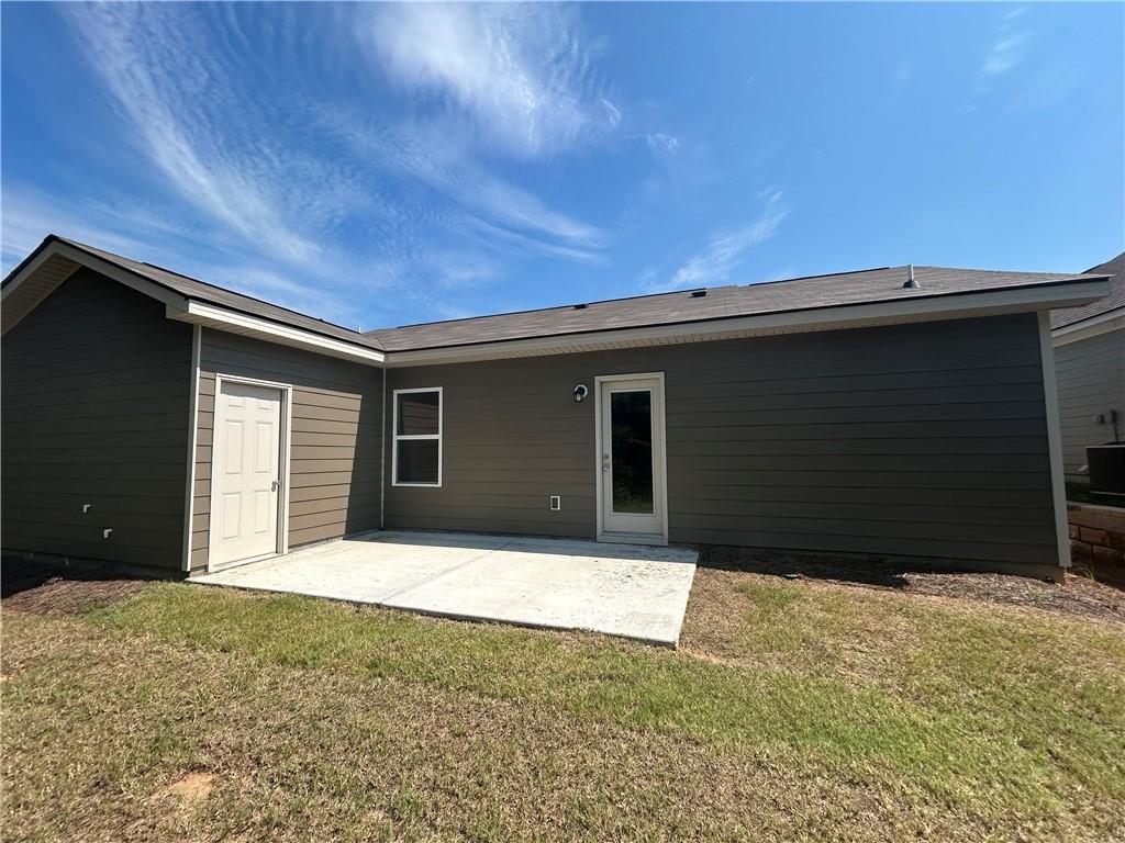 Covered back patio with sliding door on gray-sided 1-story home, grassy yard in Summer Vineyard, Phenix City, Alabama