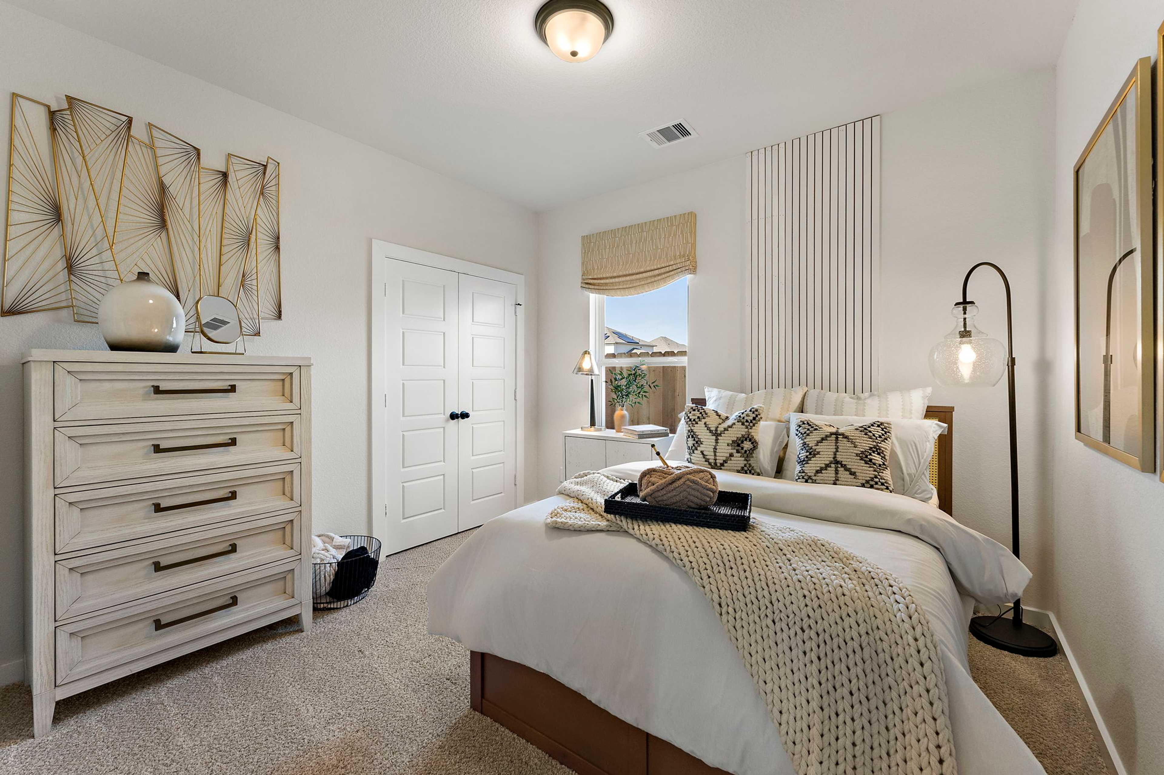 Cozy master bedroom at Sundance Cove in Crosby Texas with white bed neutral bedding wooden dresser and gold wall art